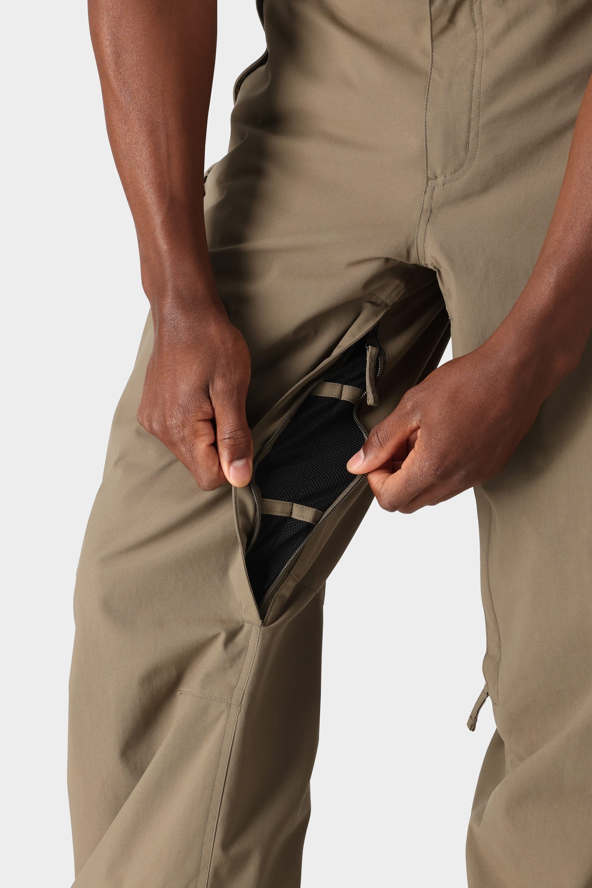 A person in tan 686 Mens Standard Shell Pants opens a zippered thigh vent, revealing breathable black mesh—highlighting the 10k waterproofing and secure pockets of these affordable shell pants by 686.