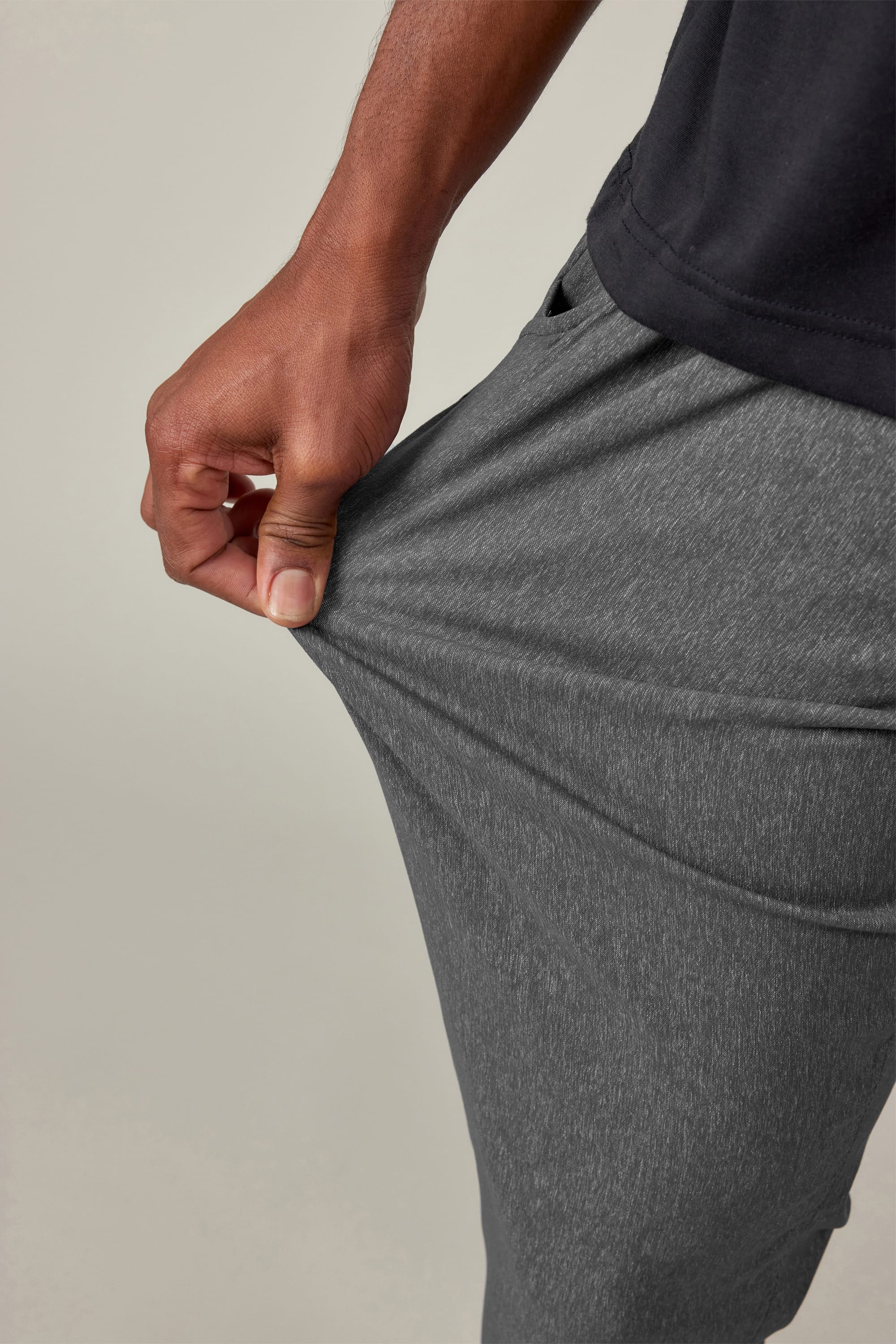A man in black shirt stretches the fabric of the 686 Men's Everywhere® Pant - Slim Fit, showing off the pants' impressive flexibility and breathability.