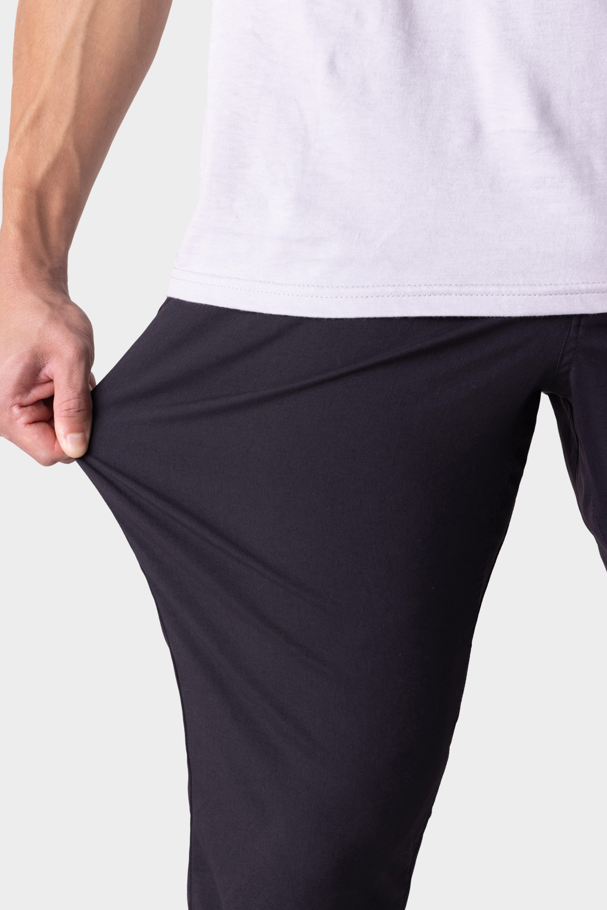 A person wearing the 686 Men's Everywhere® Pant - Relaxed Fit stretches the fabric with one hand, showcasing the stretchiness and flexibility of these 686 pants designed for all-day comfort.
