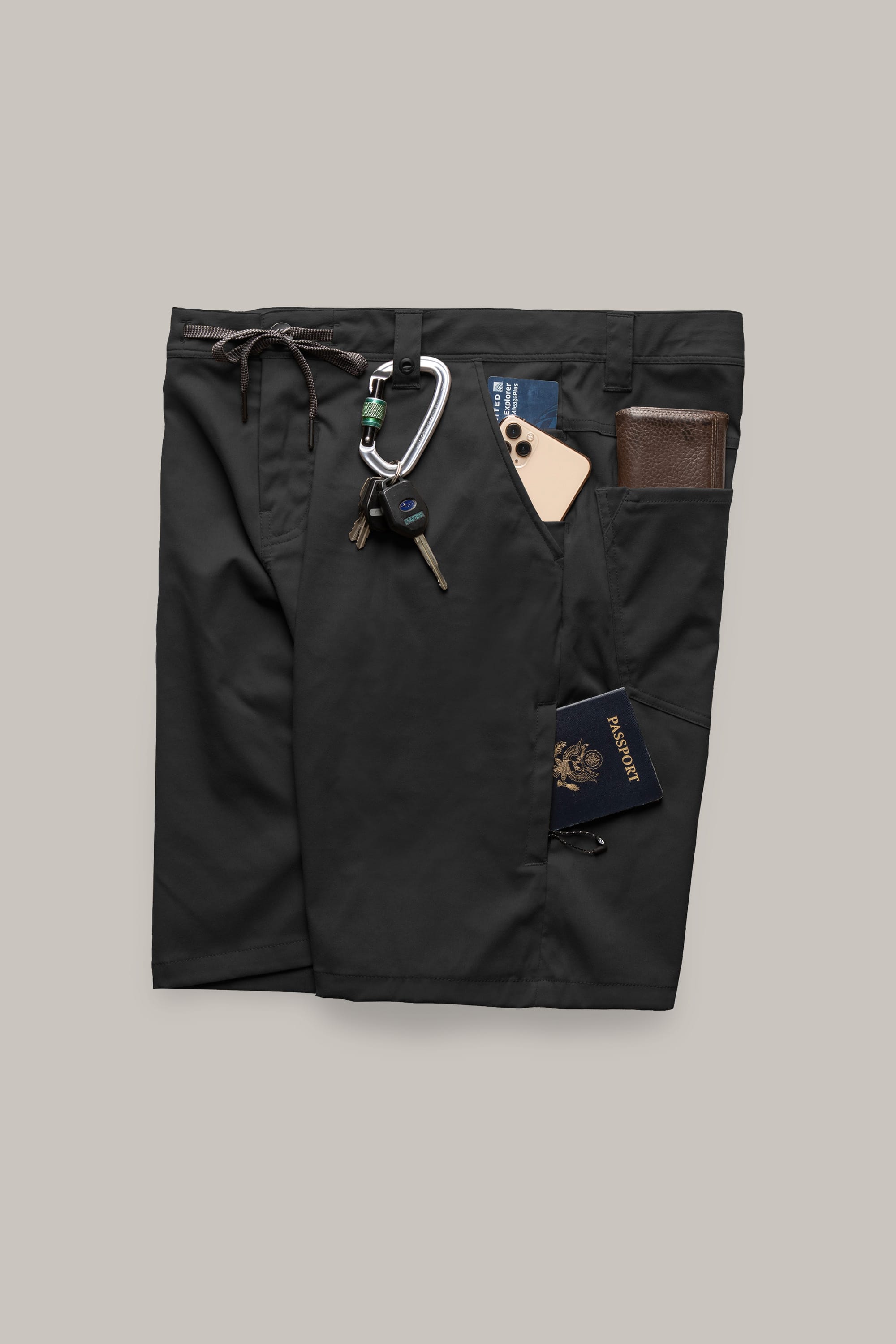 The 686 Everywhere® Hybrid Short by 686 is shown flat with pockets holding a carabiner with keys, a phone, a brown wallet, and a blue passport, highlighting the breathable design against a plain light background.