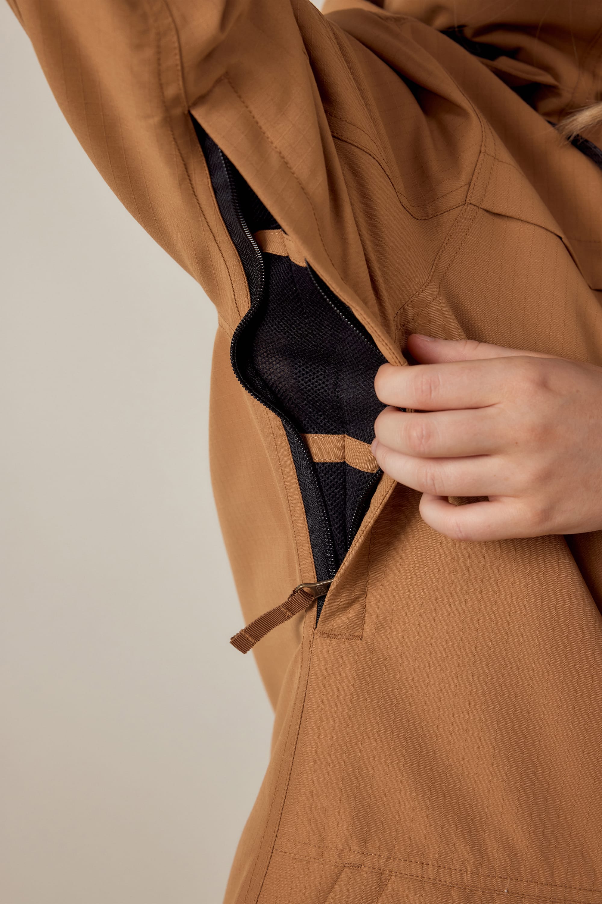 A close-up shows a hand unzipping the underarm vent of a 686 Womens Spirit Insulated Jacket, revealing its black mesh lining.