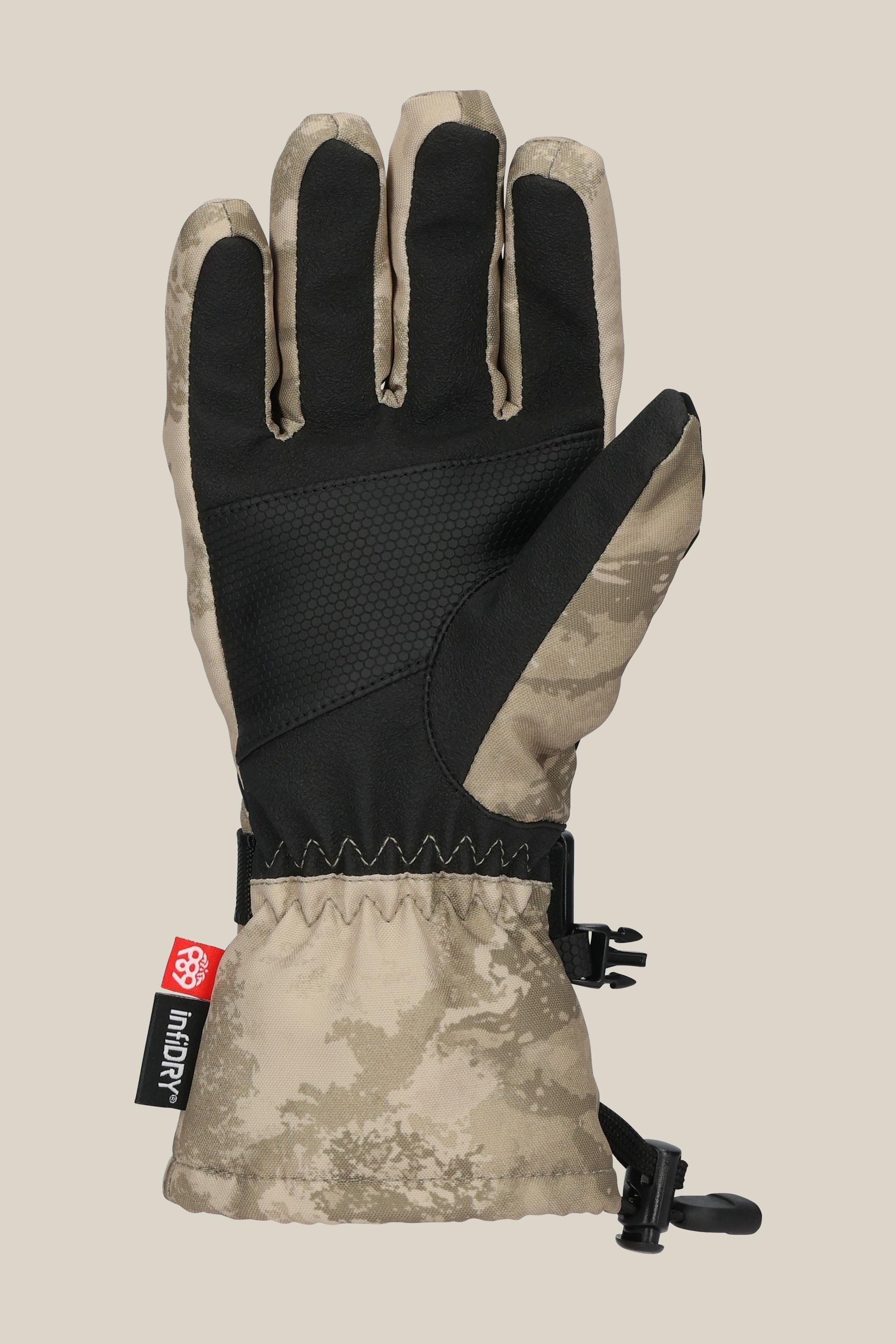 The 686 Youth Heat Glove by 686 features a tan and black camouflage design, textured palm, black adjustable wrist strap, and a small red and black tag—shown palm up on a beige background—ideal for keeping fingers warm in cold weather.