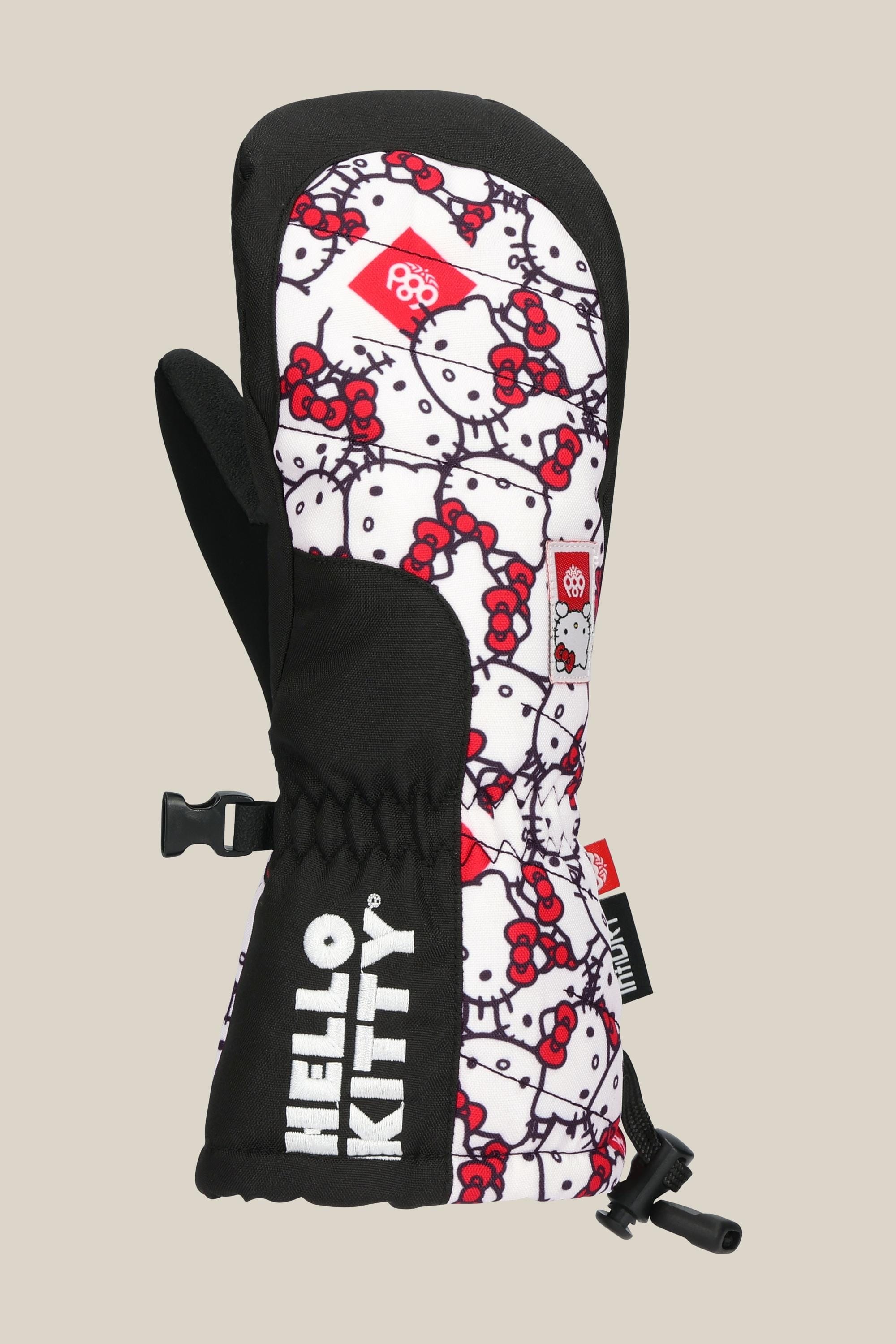 The 686 Youth Heat Mitt by 686 features a black and white Hello Kitty face pattern with red bows, a red tag, adjustable wrist strap, and bold HELLO KITTY text—stylish winter accessories to keep hands warm.