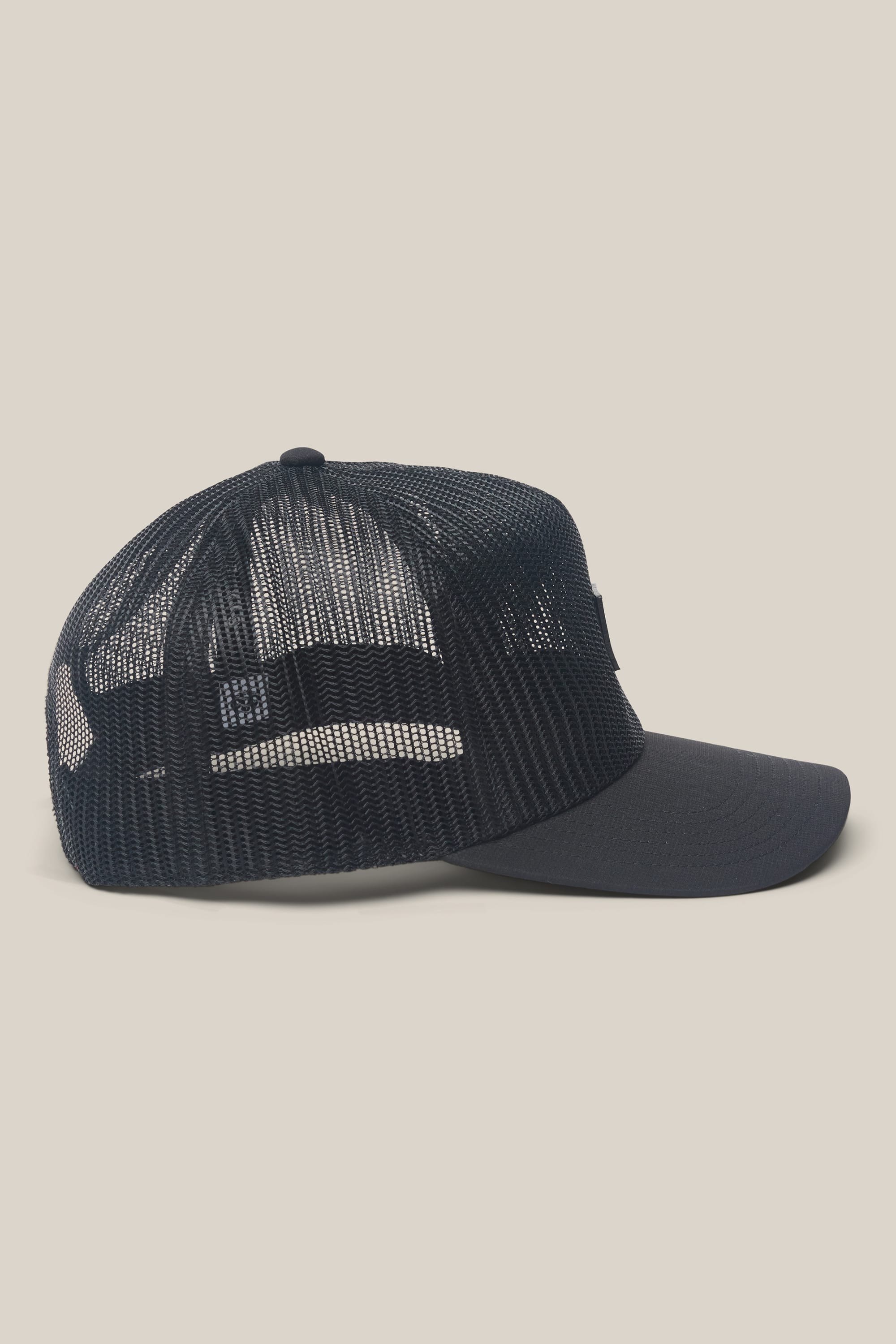 The 686 High-Pro Knockout Structured 5 Panel Hat by 686, a black mesh trucker hat ideal for men, is displayed from the side against a light beige background. It features a curved brim and an adjustable snapback closure.