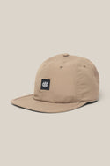 The 686 Low-Pro Adventure Unstructured 6 Panel Hat is a beige men‚Äôs poly-cotton cap with a curved brim, visible stitching, and a black front patch featuring the white 686 logo, shown on a light beige background.