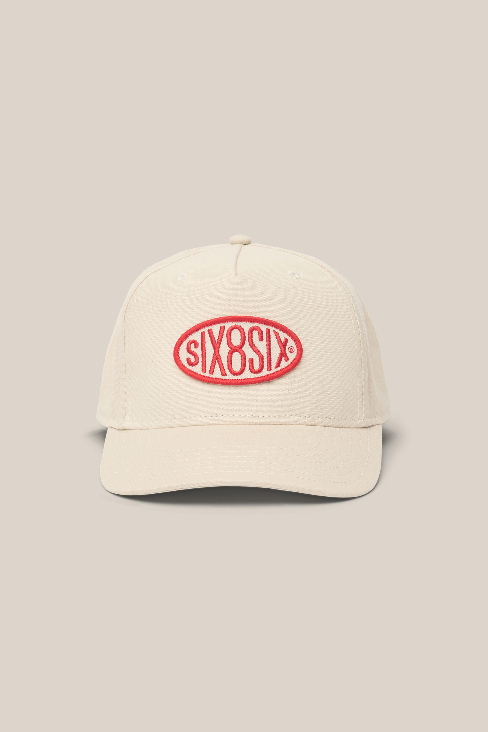 The 686 High-Pro 92 Structured 5 Panel Hat is a beige men's baseball cap by 686, made from a polyester-cotton blend. It features a curved brim and a red oval patch embroidered with "six8six" in red on the front.