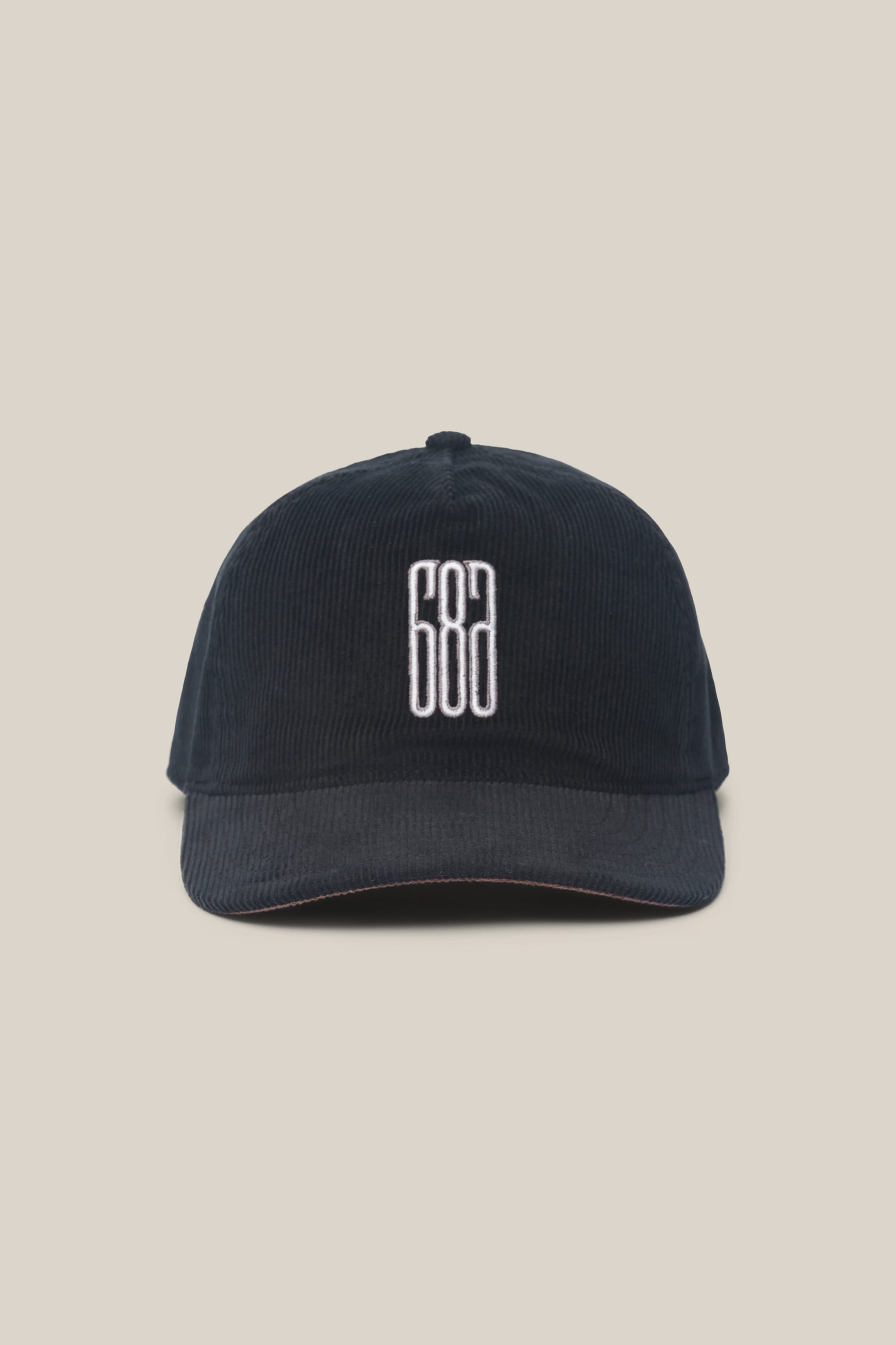 The 686 Mid-Pro Ghost Cord Unstructured 5 Panel Hat by 686 is a black corduroy men's hat featuring a white embroidered geometric design on the front, shown against a plain beige background.