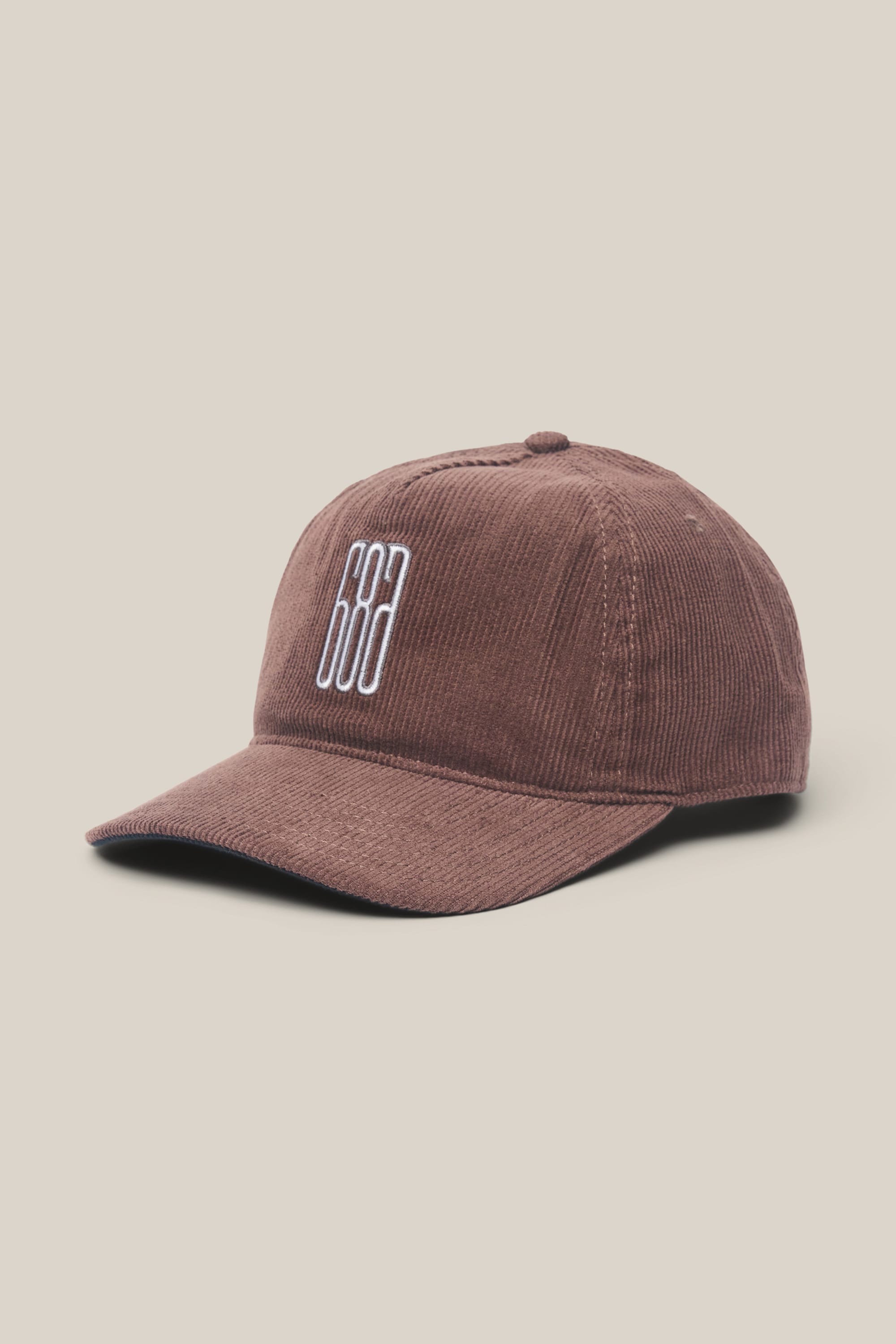 The 686 Mid-Pro Ghost Cord Unstructured 5 Panel Hat by 686 is shown against a light beige background. This men's brown corduroy baseball cap features white embroidered vertical lines on the front and is crafted from a soft polyester-cotton woven material, offering both comfort and timeless style.