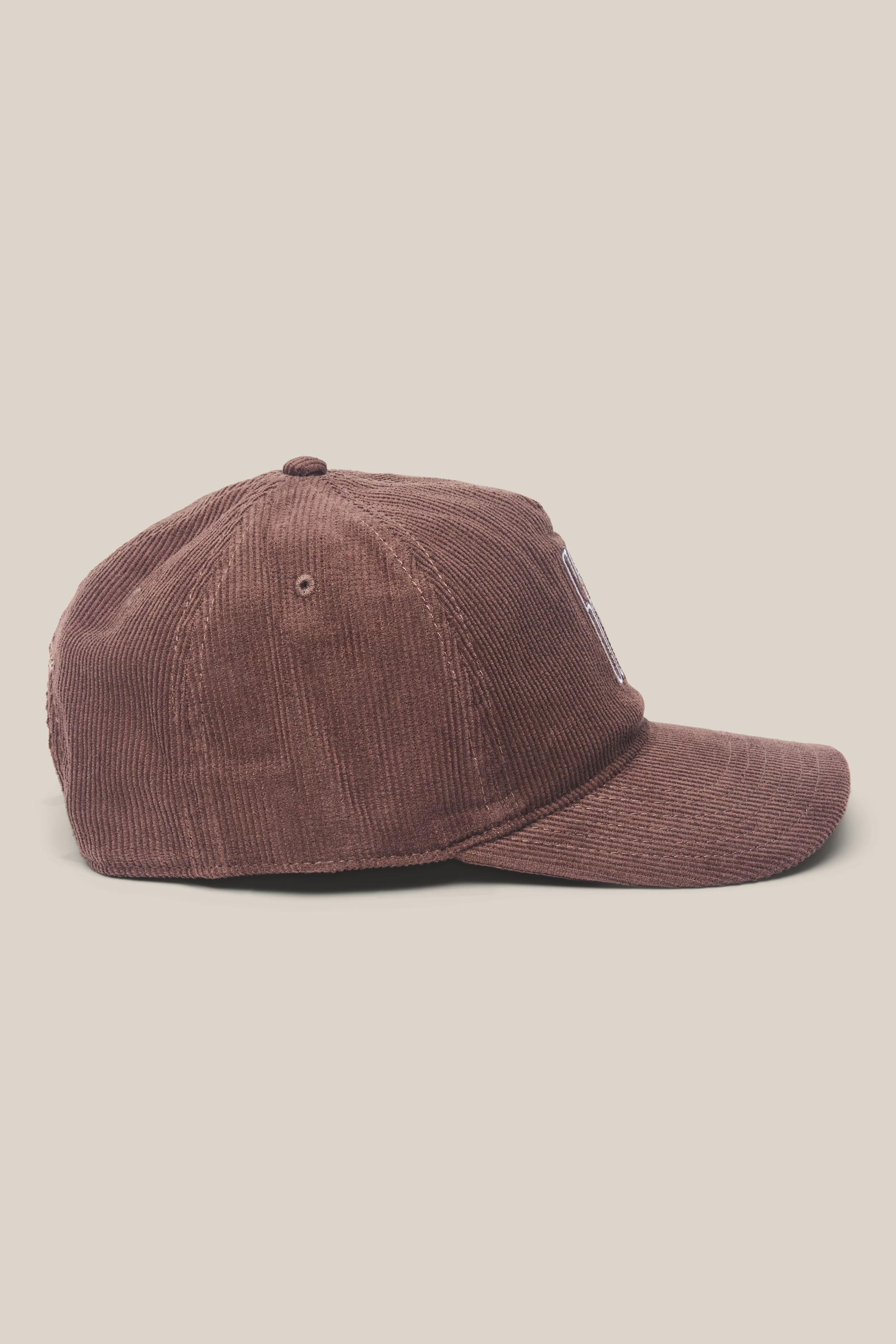 The 686 Mid-Pro Ghost Cord Unstructured 5 Panel Hat by 686 is displayed in side profile against a light beige background. Made from a woven polyester-cotton blend, this brown hat features visible corduroy texture and stitching, a curved brim, and a button on top.
