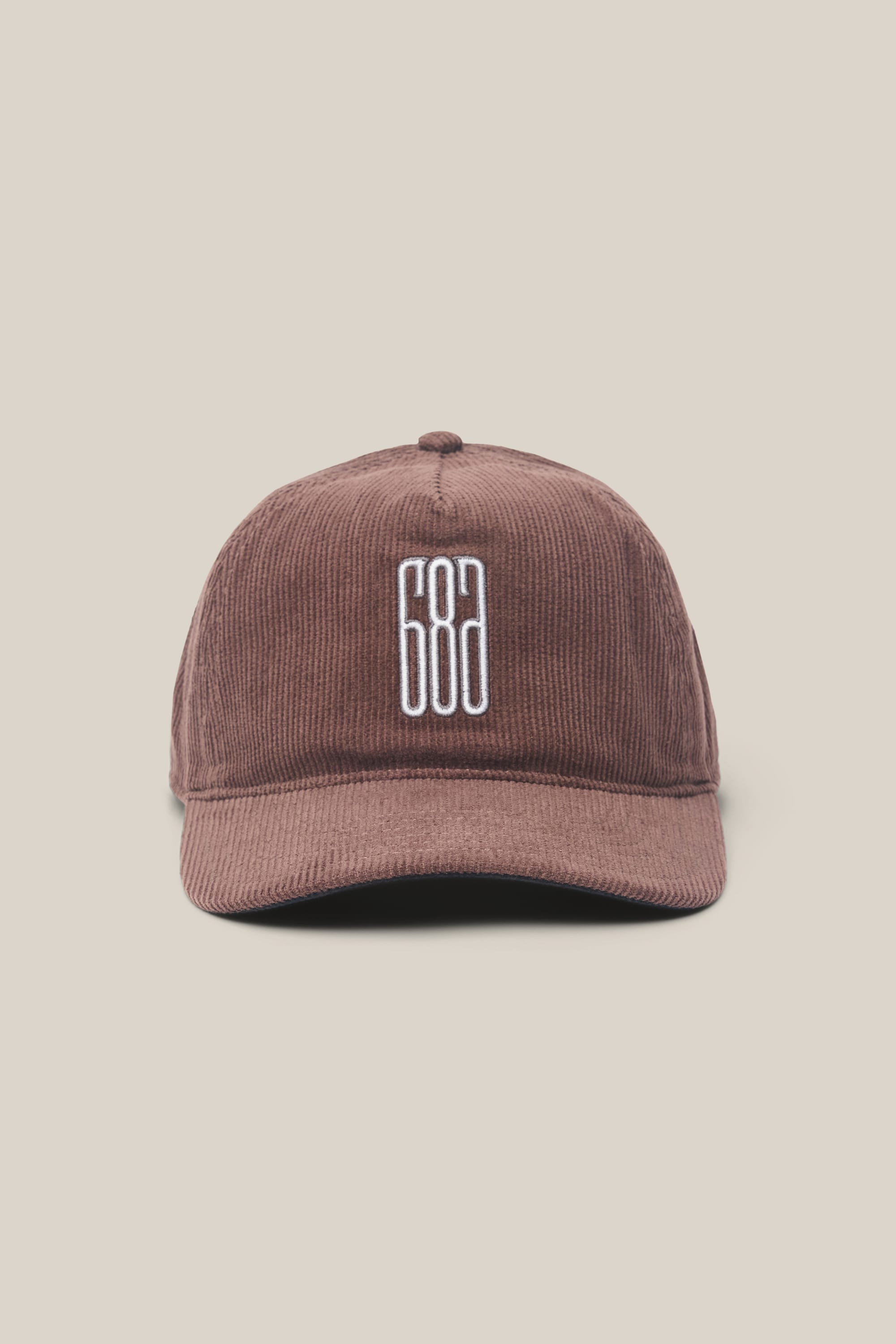 The 686 Mid-Pro Ghost Cord Unstructured 5 Panel Hat by 686 is a men's brown corduroy baseball cap featuring a white embroidered 686 logo on the front, crafted from premium polyester-cotton woven fabric and shown against a plain beige background.
