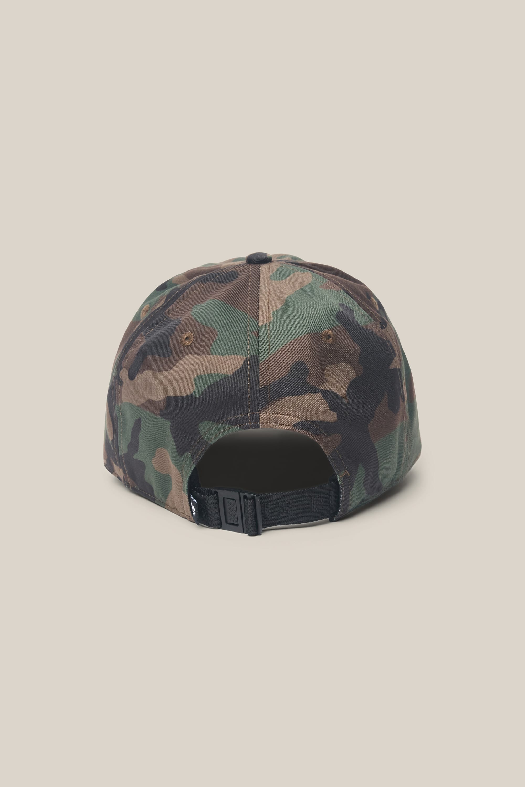 The image features the 686 Low-Pro Unwork Unstructured 6 Panel Hat by 686, displayed from the back. This camouflage polyester-cotton hat has an adjustable black strap and a small button on top, set against a plain off-white background.