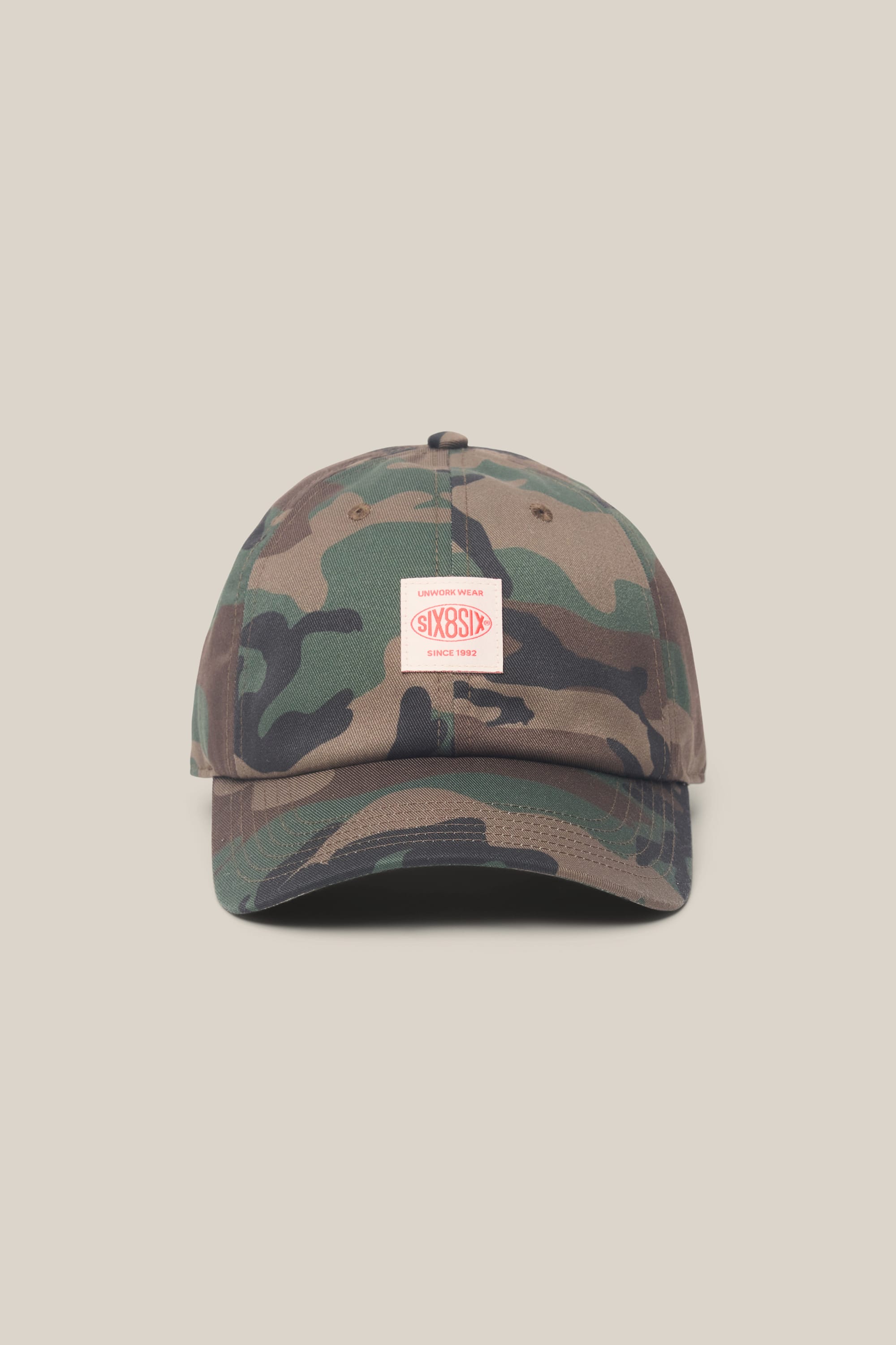 Here's a rewritten version using your product data: The 686 Low-Pro Unwork Unstructured 6 Panel Hat by 686 is a men's camouflage baseball cap featuring a curved brim and a white rectangular patch with red text on the front. Crafted from durable polyester-cotton blend and set against a simple beige backdrop, this woven hat delivers classic style with rugged appeal.