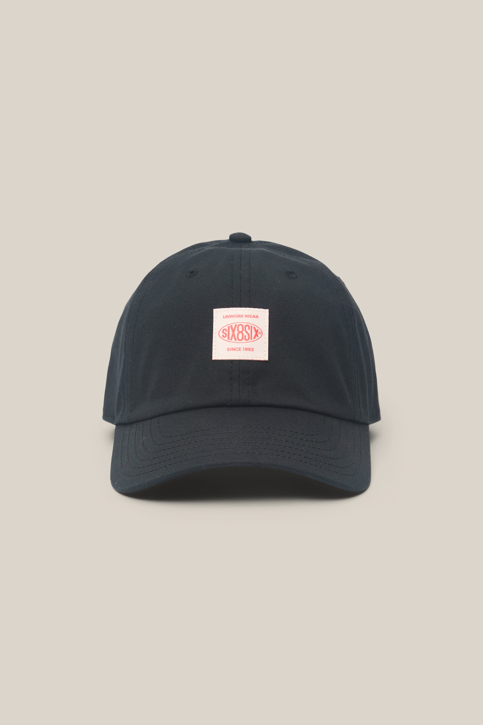 The 686 Low-Pro Unwork Unstructured 6 Panel Hat by 686 is a black men's polyester-cotton hat with a curved brim and a small rectangular white and red logo patch on the front, shown on a plain beige background.