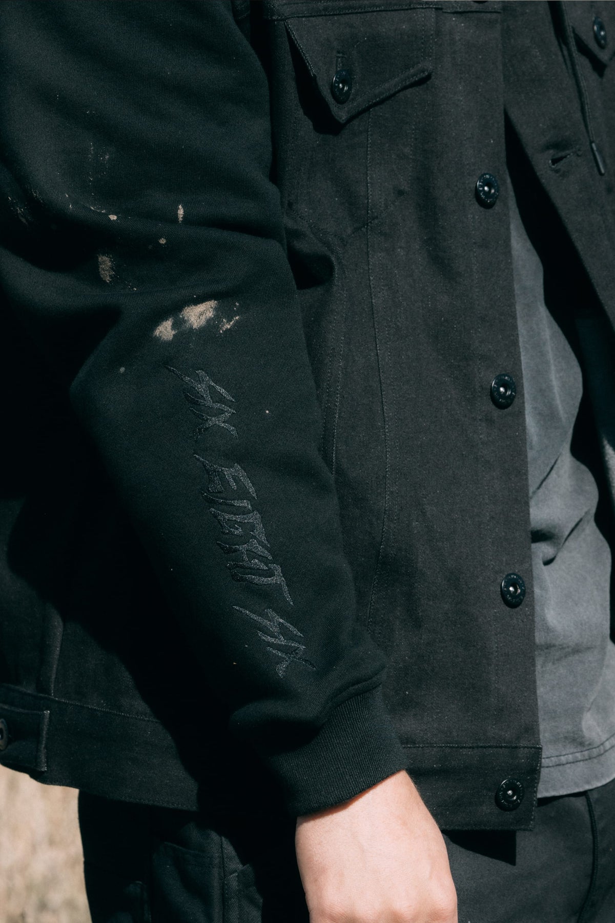 Close-up of a black 686 Men’s Metalhead Trucker Jacket sleeve with ribbed cuffs, faint embroidery on the forearm, and distressed detailing near the elbow.