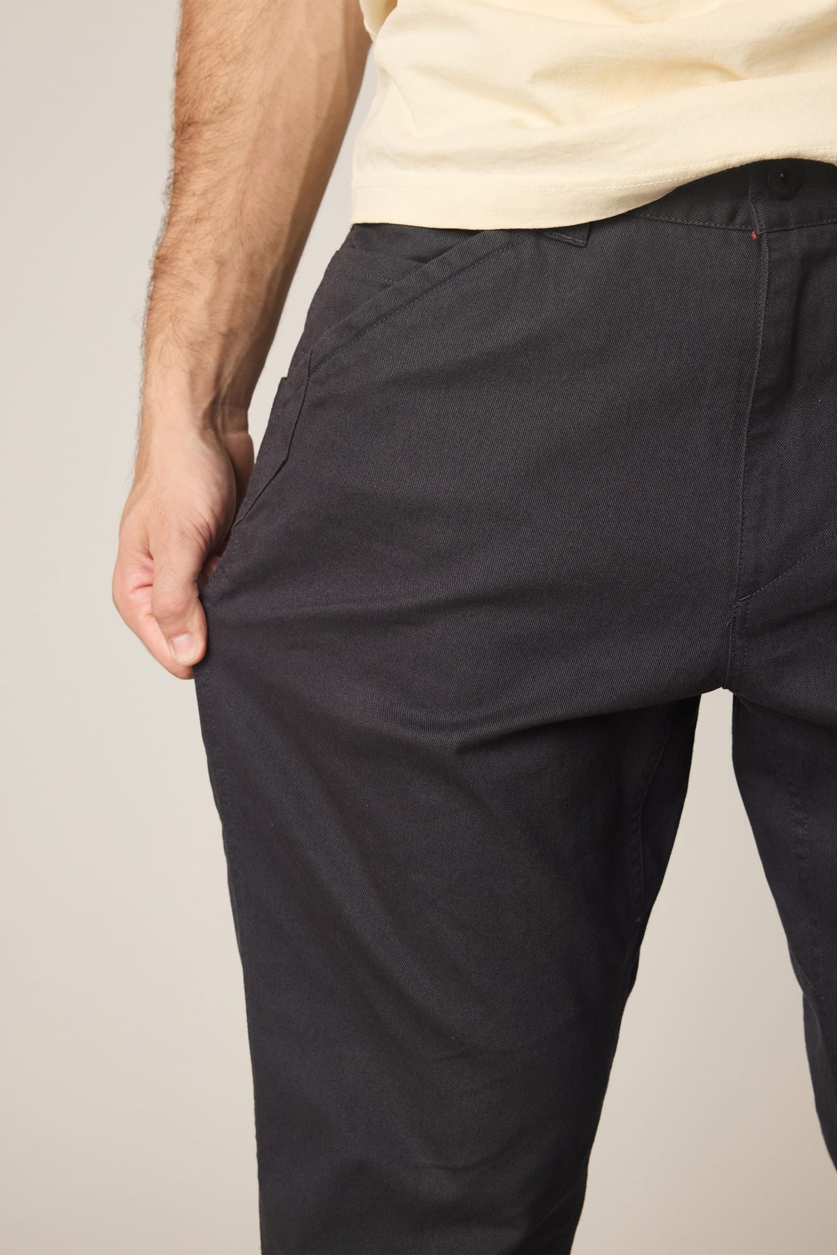 A person wearing 686 Men’s Unwork® Tradesman Pant - Relaxed Fit in dark nylon and a light-colored t-shirt, pulling at the side pocket.