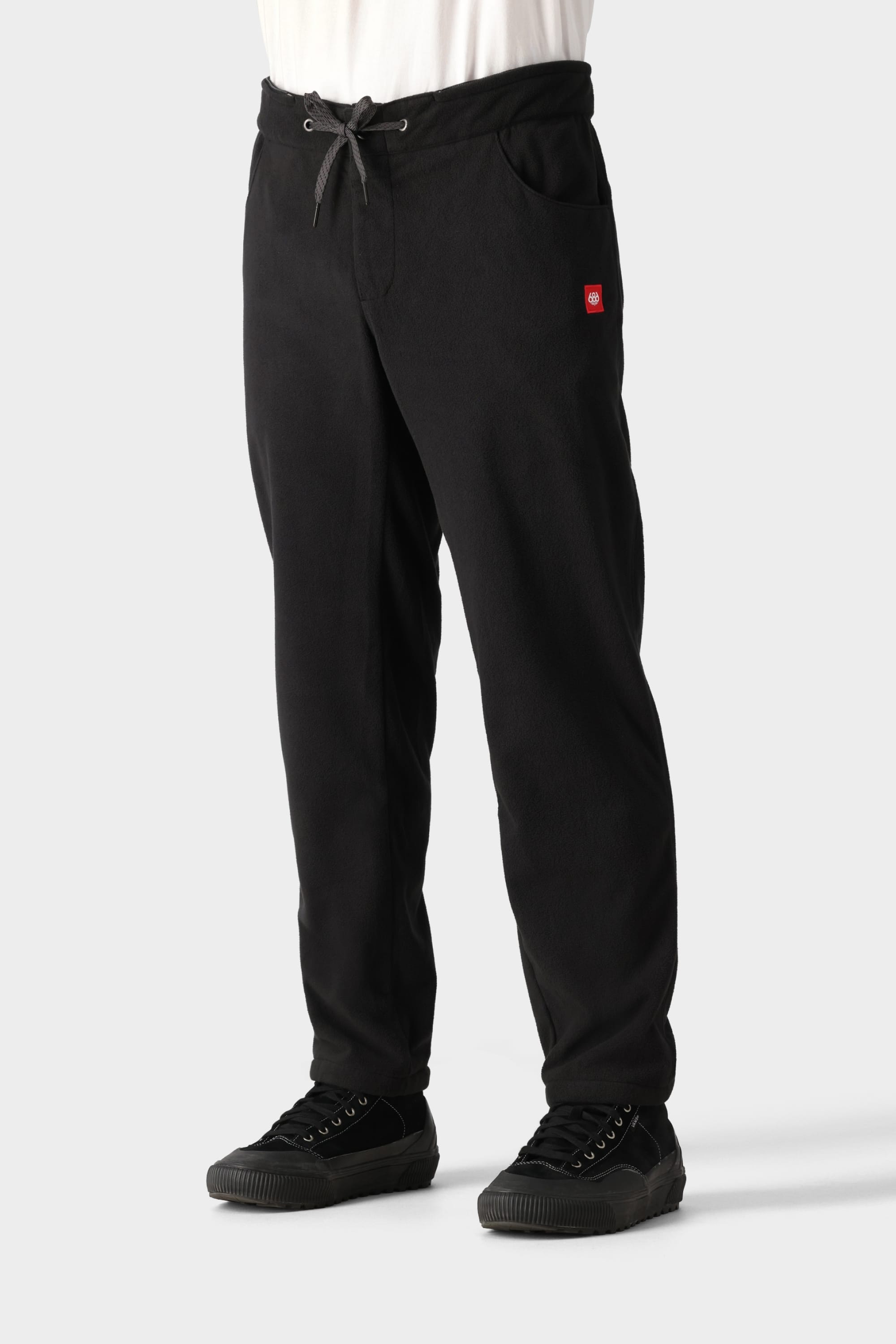 A person wearing 686 Men’s SMARTY® 3-in-1 Cargo Pants with a small red logo on the pocket and black sneakers, standing against a plain light gray background.