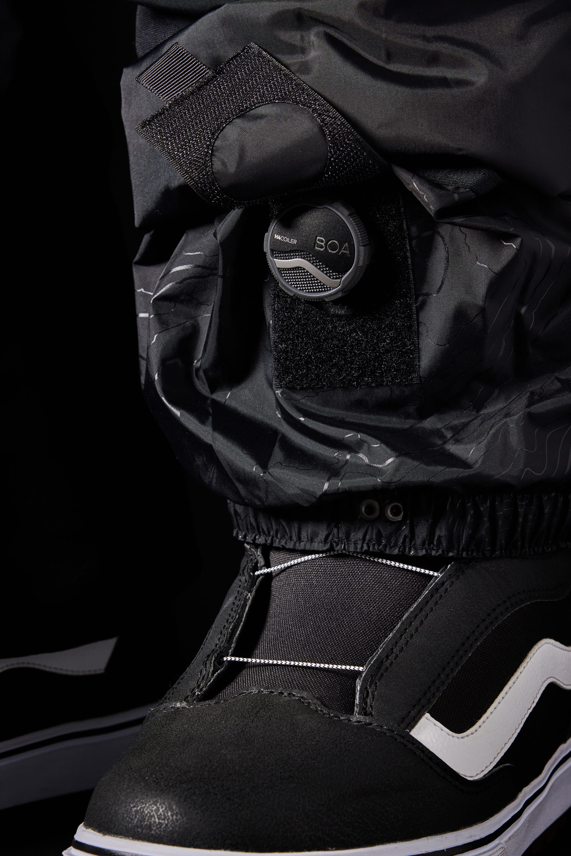 Close-up of a black and white sneaker with the 686 Men’s SMARTY® 3-in-1 Cargo Pant featuring a BOA dial and Velcro strap fastening system over the shoe.