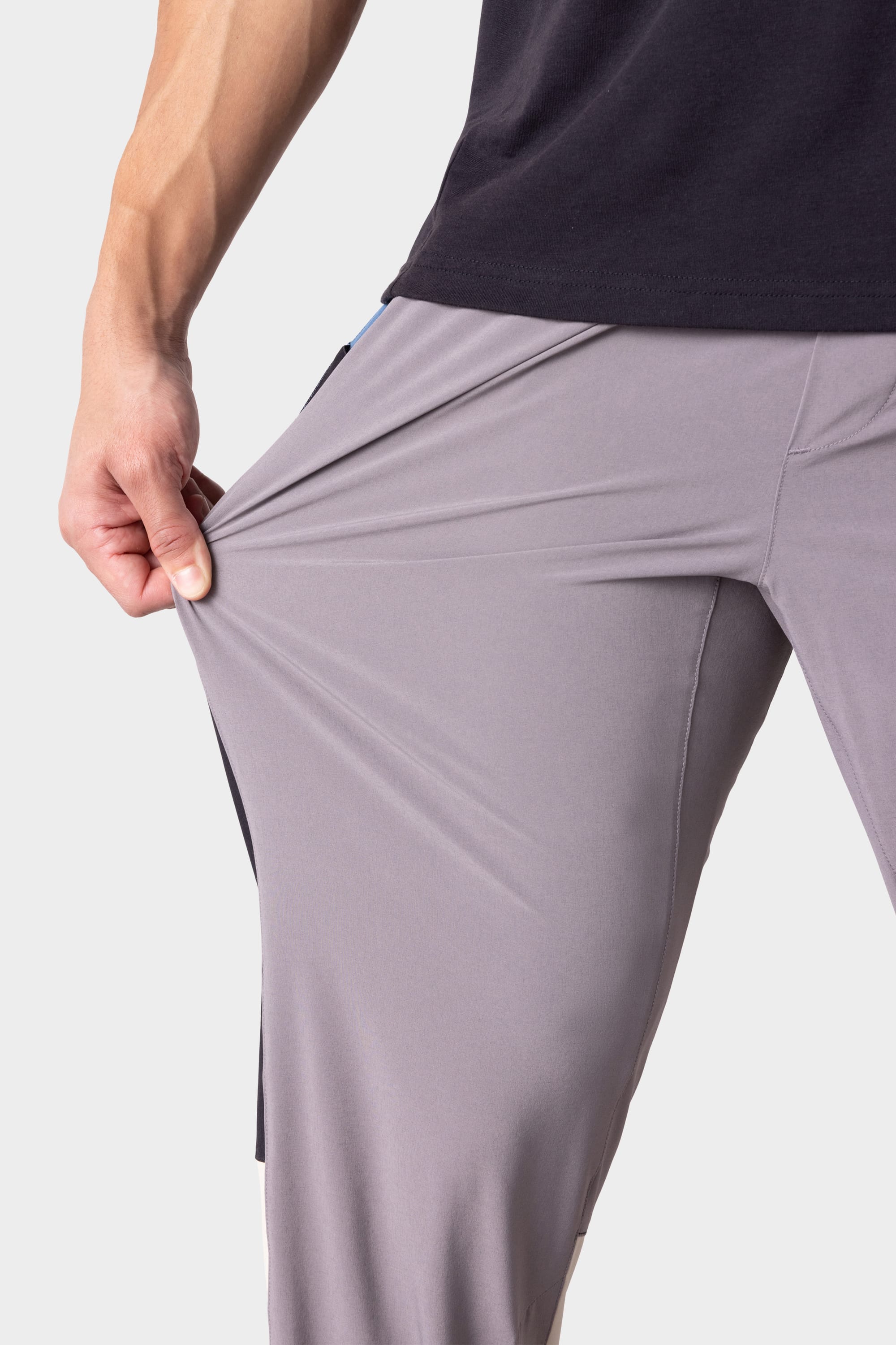 A person wearing 686 Men's ATP Stretch Performance Pant in light gray stretches the fabric with one hand, showing the flexibility of these 686 pants.