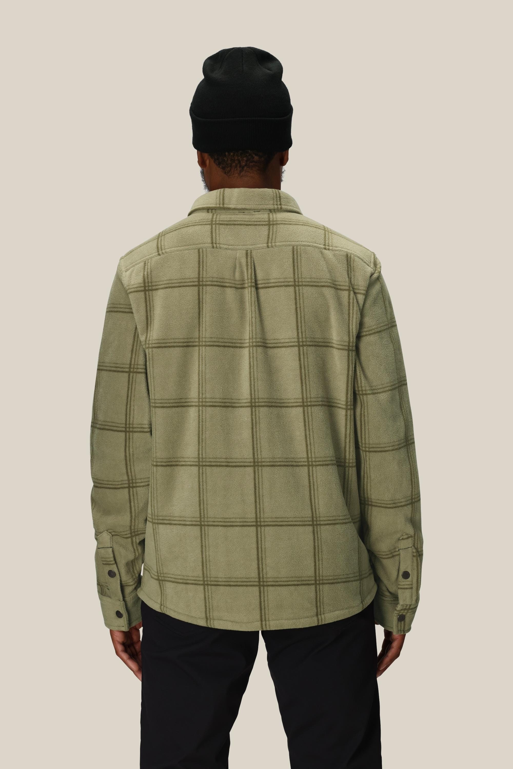 A person is shown from the back, wearing the 686 Mens Sierra Fleece Flannel and a black beanie against a beige background—this 686 piece is the perfect spring riding layer.