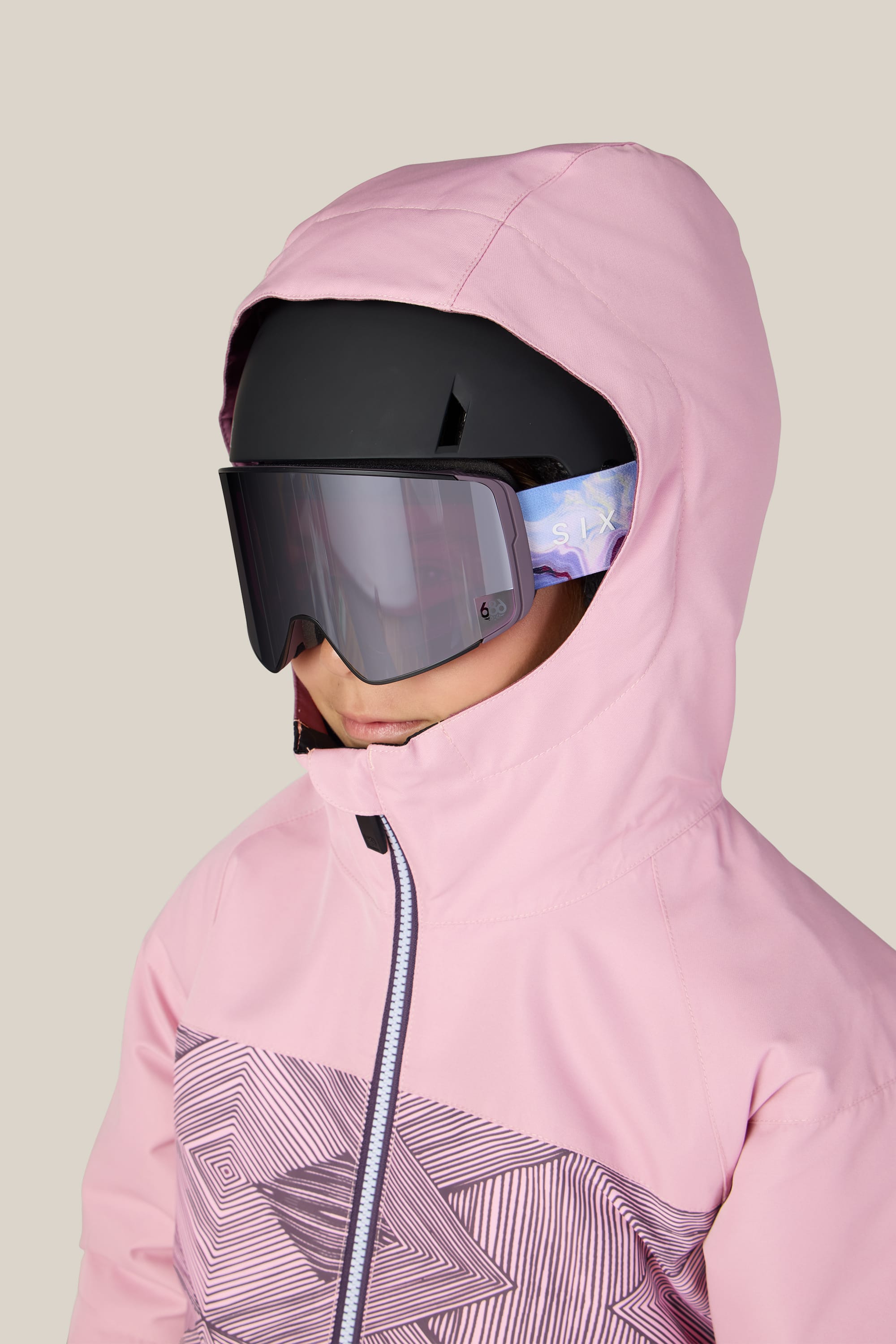 A person wearing the 686 Girls’ Athena™ Insulated Jacket in pink, along with a black ski helmet and large reflective ski goggles, is facing slightly to the left against a plain background.