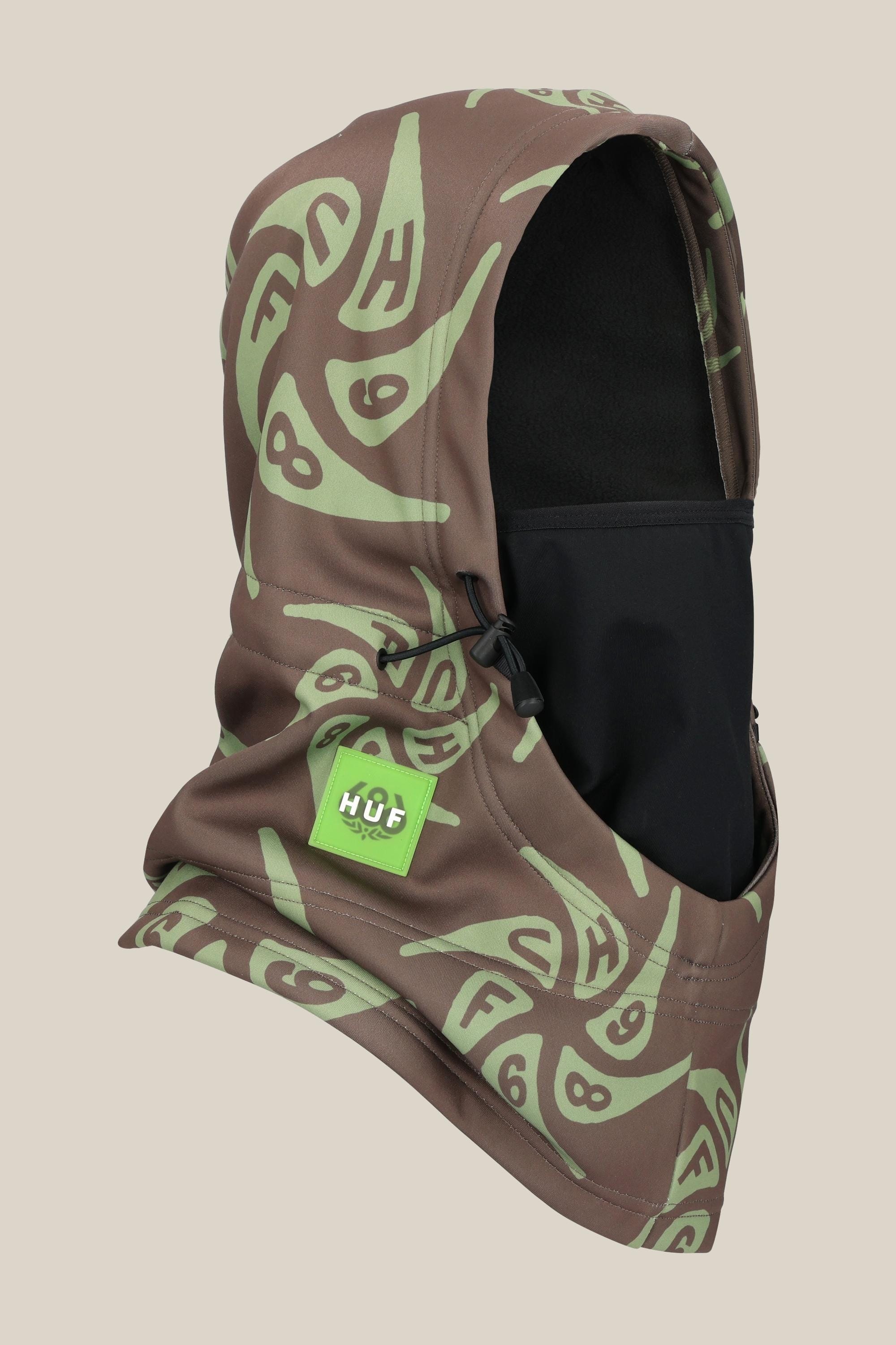 The 686 Patriot Bonded Hood by 686 features a brown and green abstract pattern, black face covering, green logo patch, adjustable drawstring, and lightweight design. Displayed on a plain beige background.