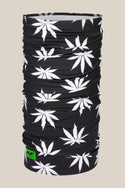 The 686 Double Layer Face Warmer by 686 is a black neck gaiter with a repeating white cannabis leaf pattern and a small neon green logo tag. The solid beige background pairs well with both high-waist and low-waist outfits.