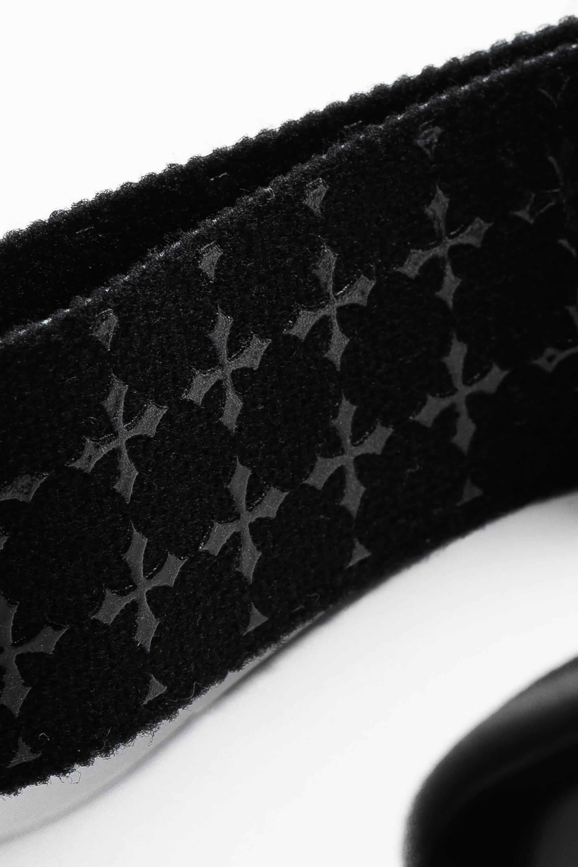 Close-up of the 686 SMARTY® Magnetic Goggle by 686, featuring black textured fabric with a glossy repeating floral or geometric pattern on a matte, soft background, shown against white.