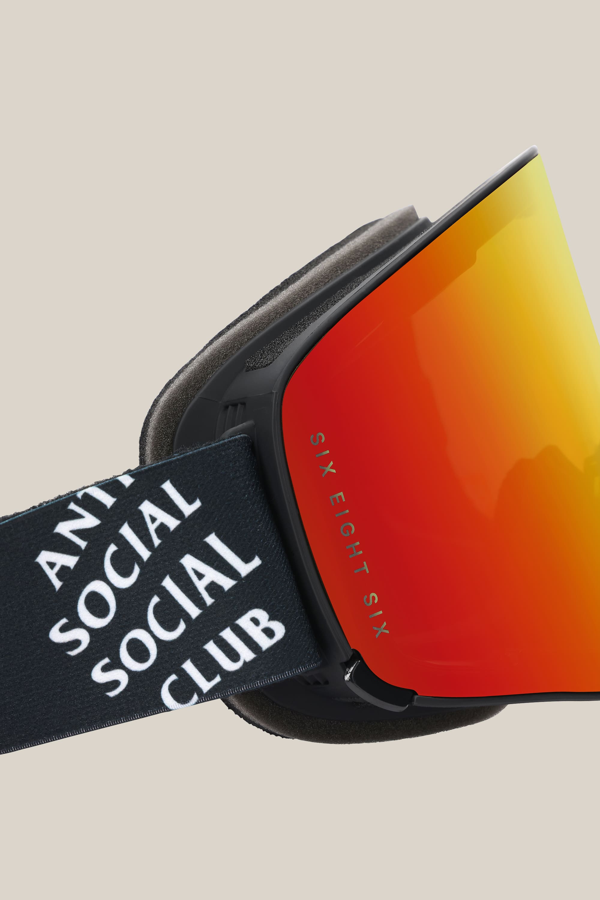Close-up of the 686 SMARTY® Magnetic Goggle featuring a reflective red-orange lens, black strap with ANTI SOCIAL SOCIAL CLUB in white, and SIX EIGHT SIX labeled on the lens side. Brand: 686.