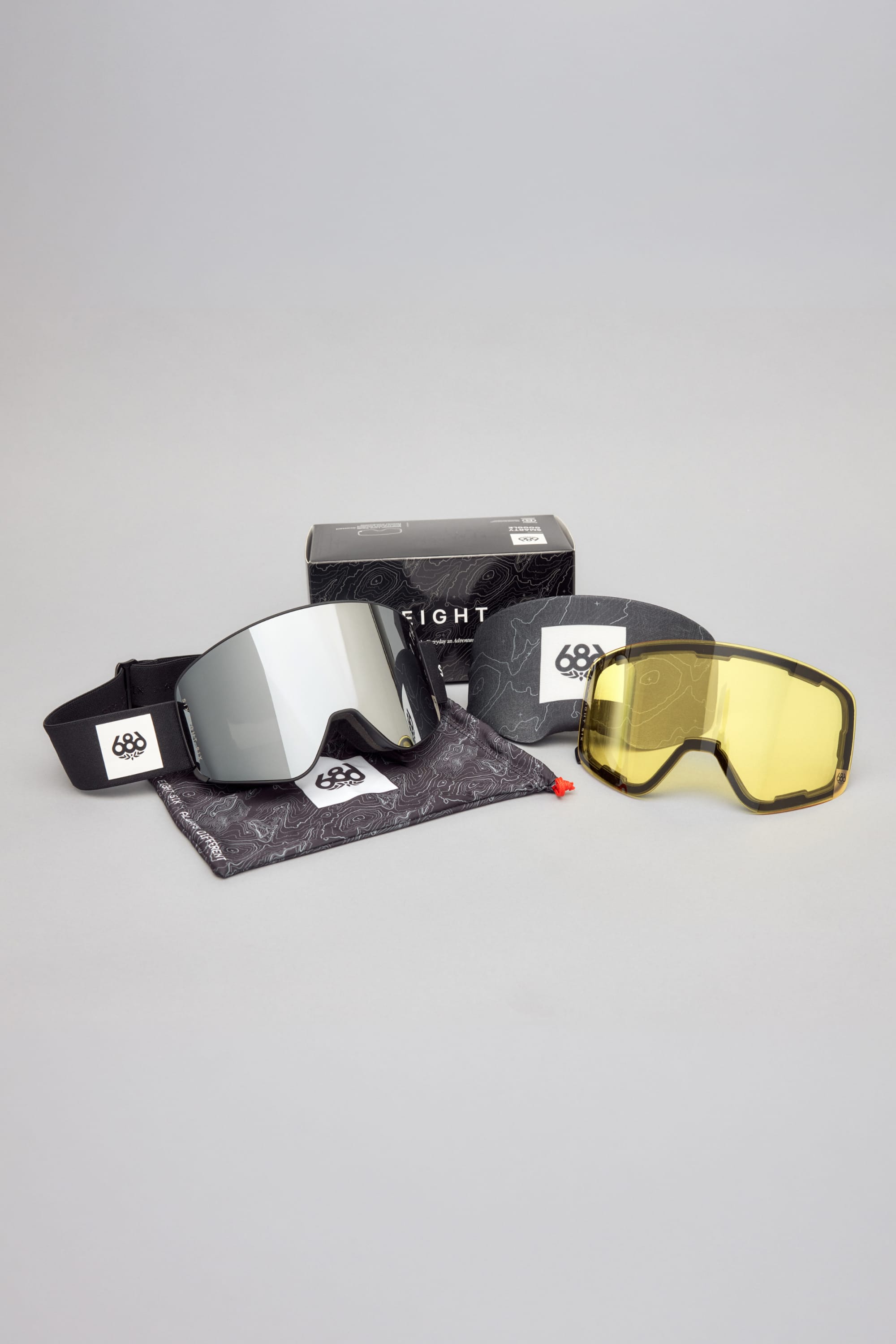 Set of 686 SMARTY® Magnetic Goggles with interchangeable lenses—one reflective and one yellow—shown alongside a branded 686 pouch and box on a light gray background.