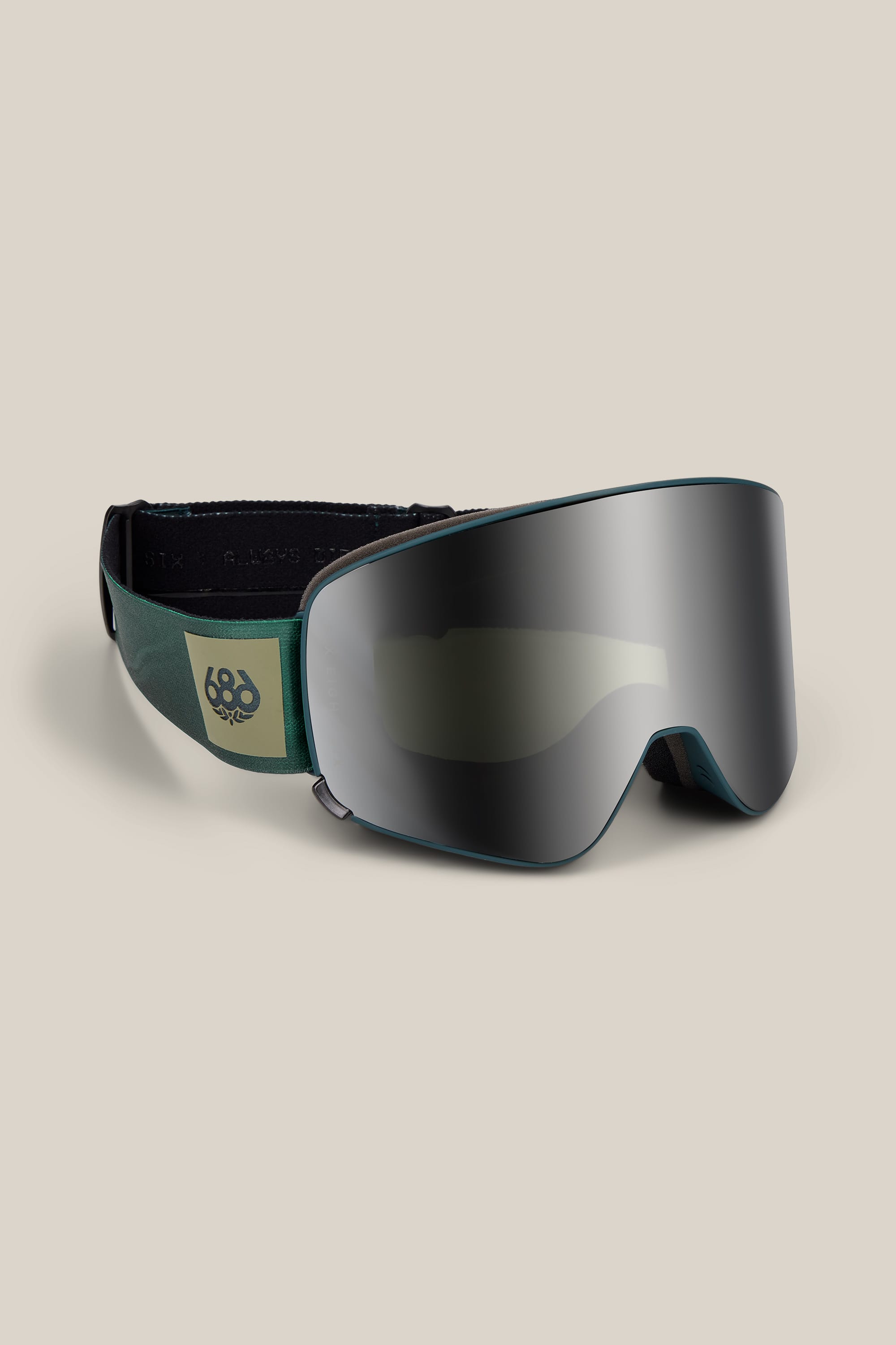 The 686 SMARTY® Magnetic Goggle by 686 features a reflective lens and a green and black adjustable strap with a yellow 686 logo, shown against a beige background.