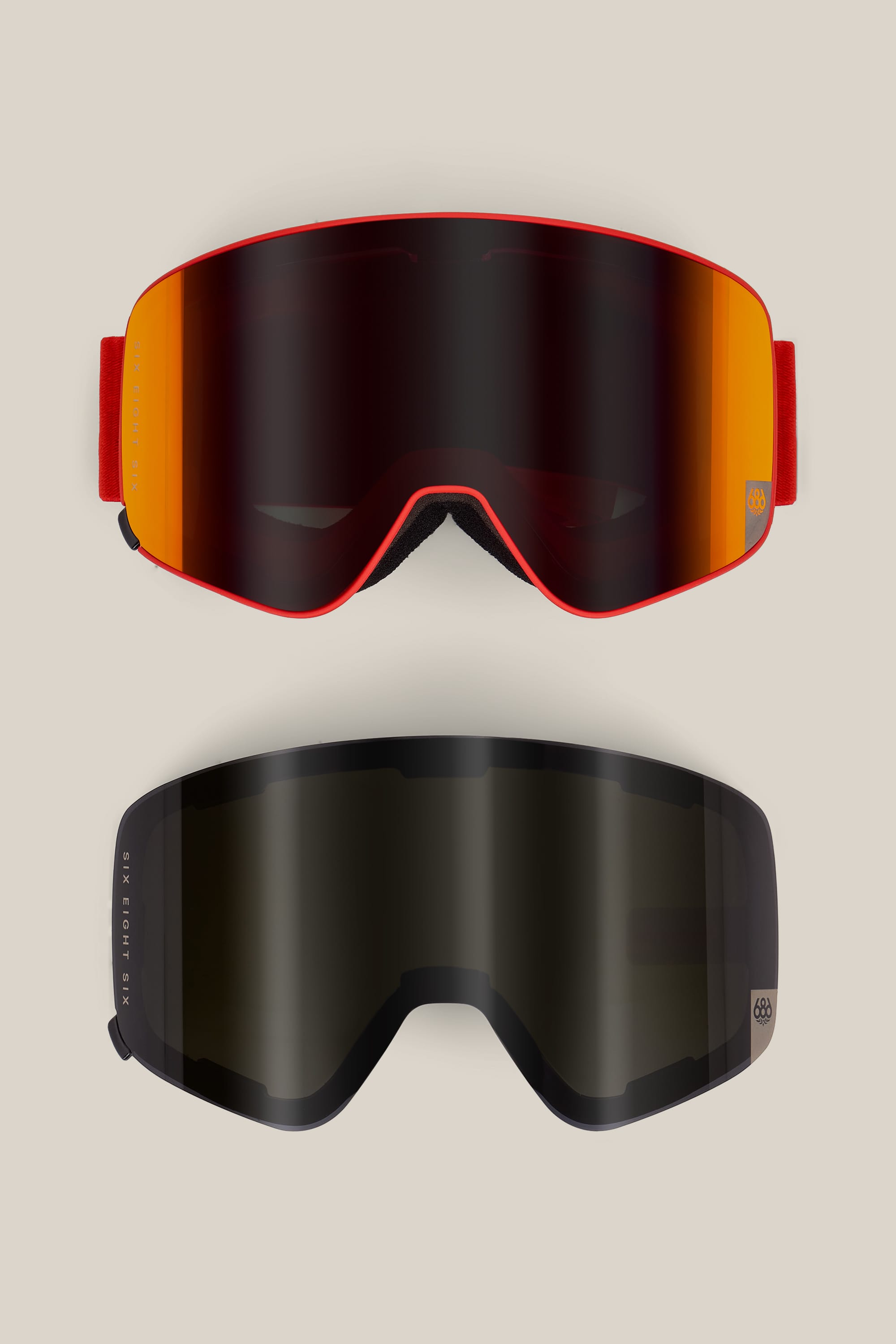 Two pairs of 686 SMARTY® Magnetic Goggles are displayed on a plain background: the top pair features a red frame with an orange mirrored lens, while the bottom pair has a black frame with a dark lens.
