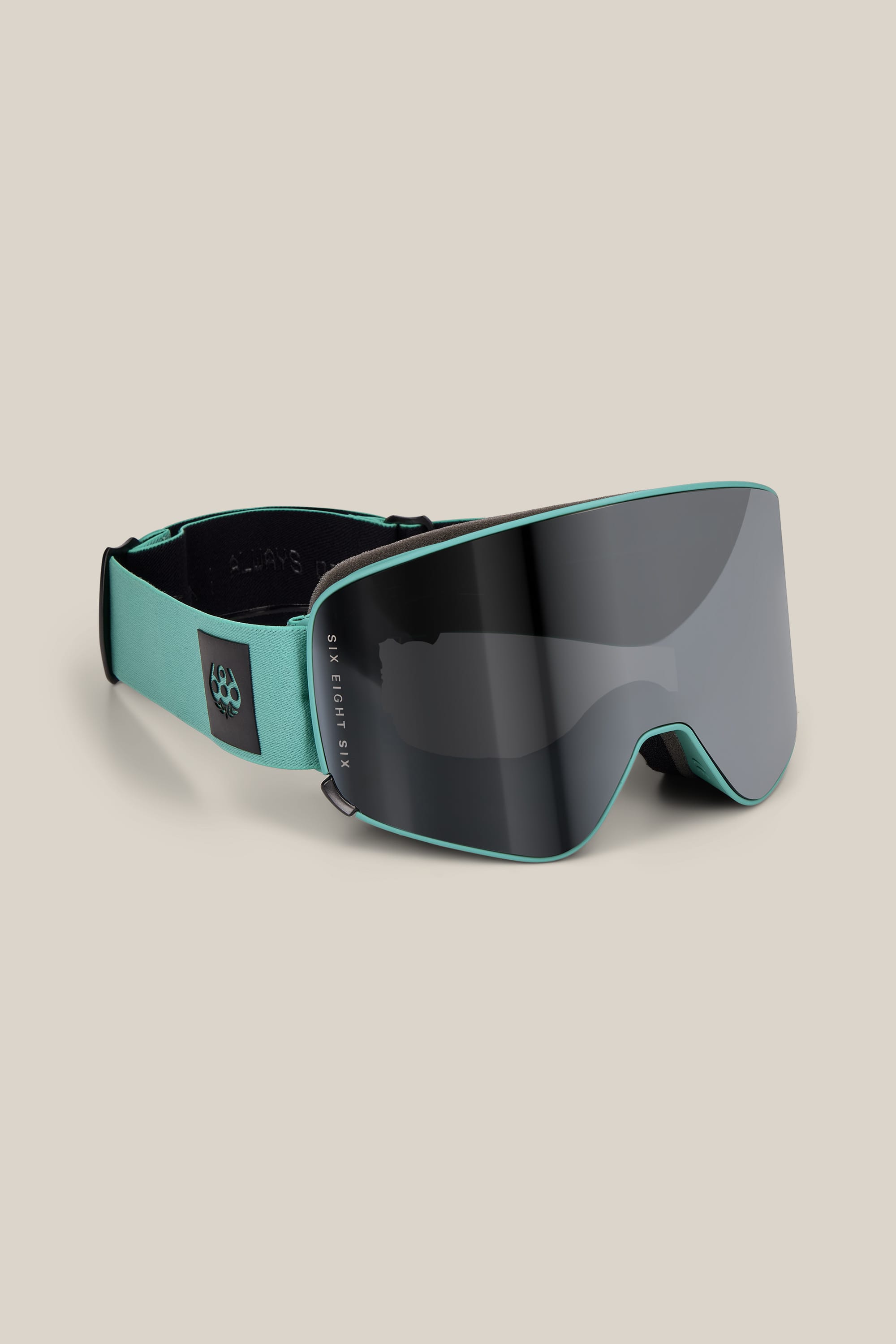 The 686 SMARTY® Magnetic Goggle by 686 features a wide, dark tinted lens and a turquoise frame and strap, displayed against a plain beige background.