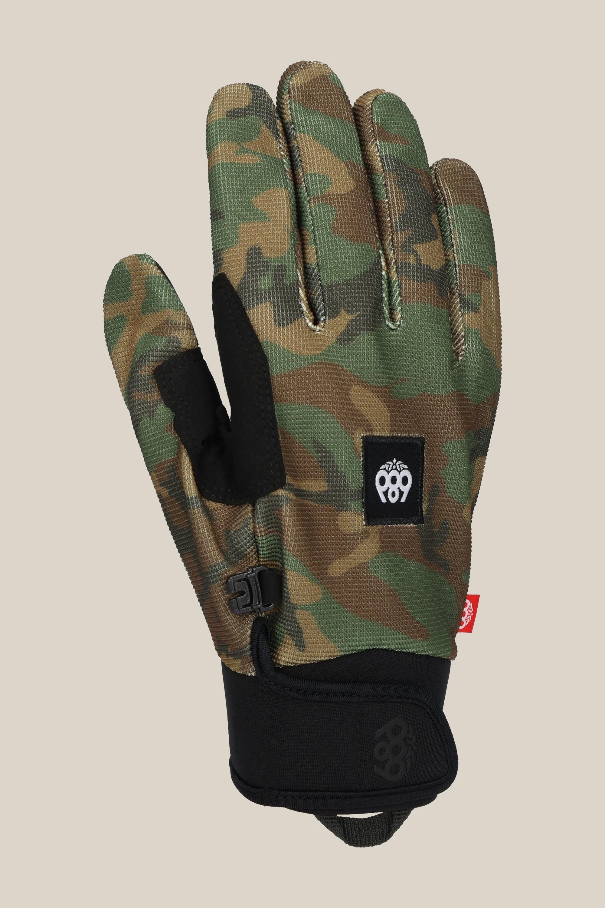 The 686 Outlaw Pipe Glove by 686 features green and brown camouflage, a black adjustable wrist strap, and a black patch with a white logo on the back. Shown palm facing the viewer.
