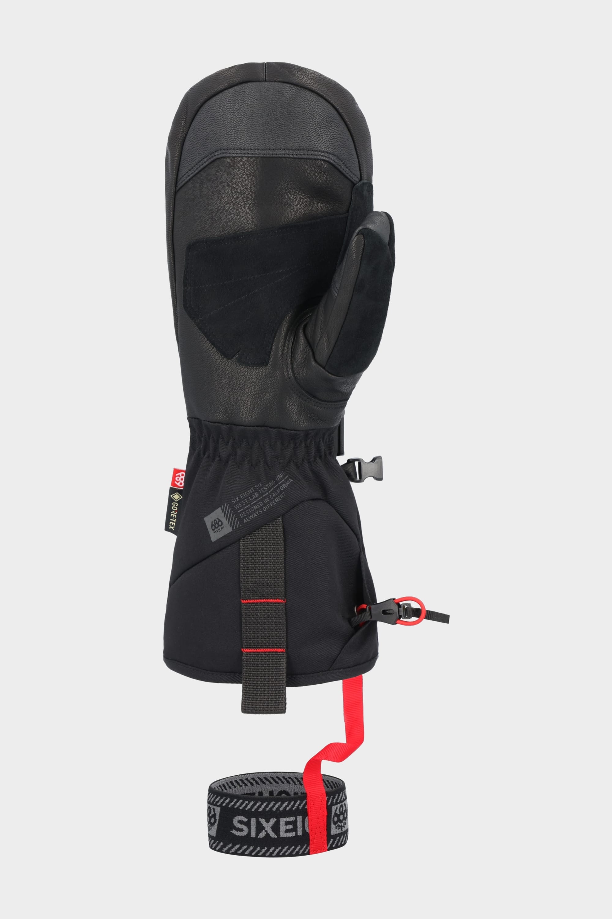 The 686 Men's GORE-TEX Leather Deep Days™ Mitt is a black insulated leather mitt with GORE-TEX waterproofing, leather accents, a reinforced palm, adjustable wrist cinch with red details, and a removable black and red SIXEIGHT SIX wrist leash.