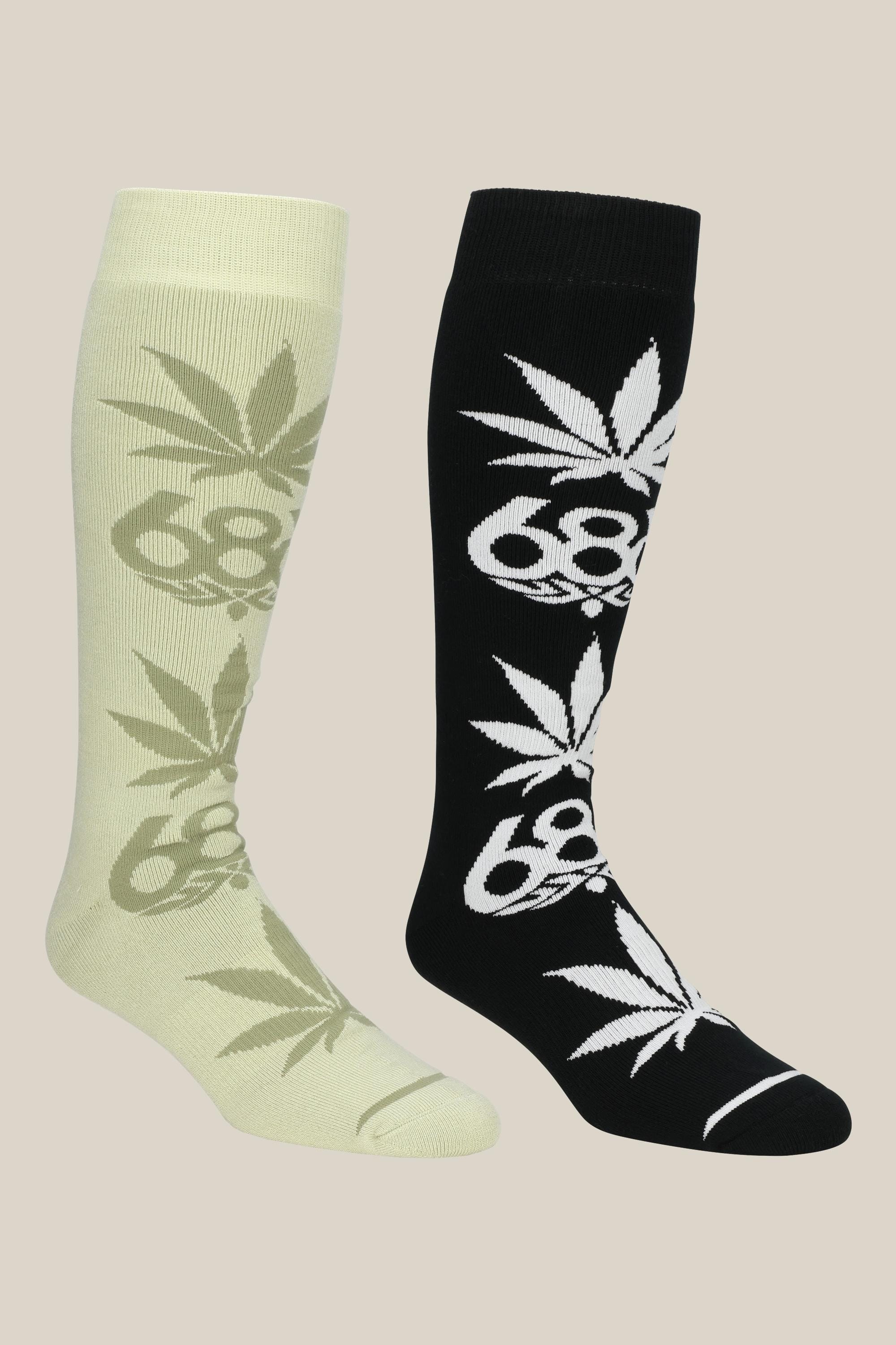 Two knee-high 686 Men's HUF Socks are shown: one light yellow with a gray cannabis leaf and '68' design, the other black with a white leaf and '68', both displayed on a plain beige background.