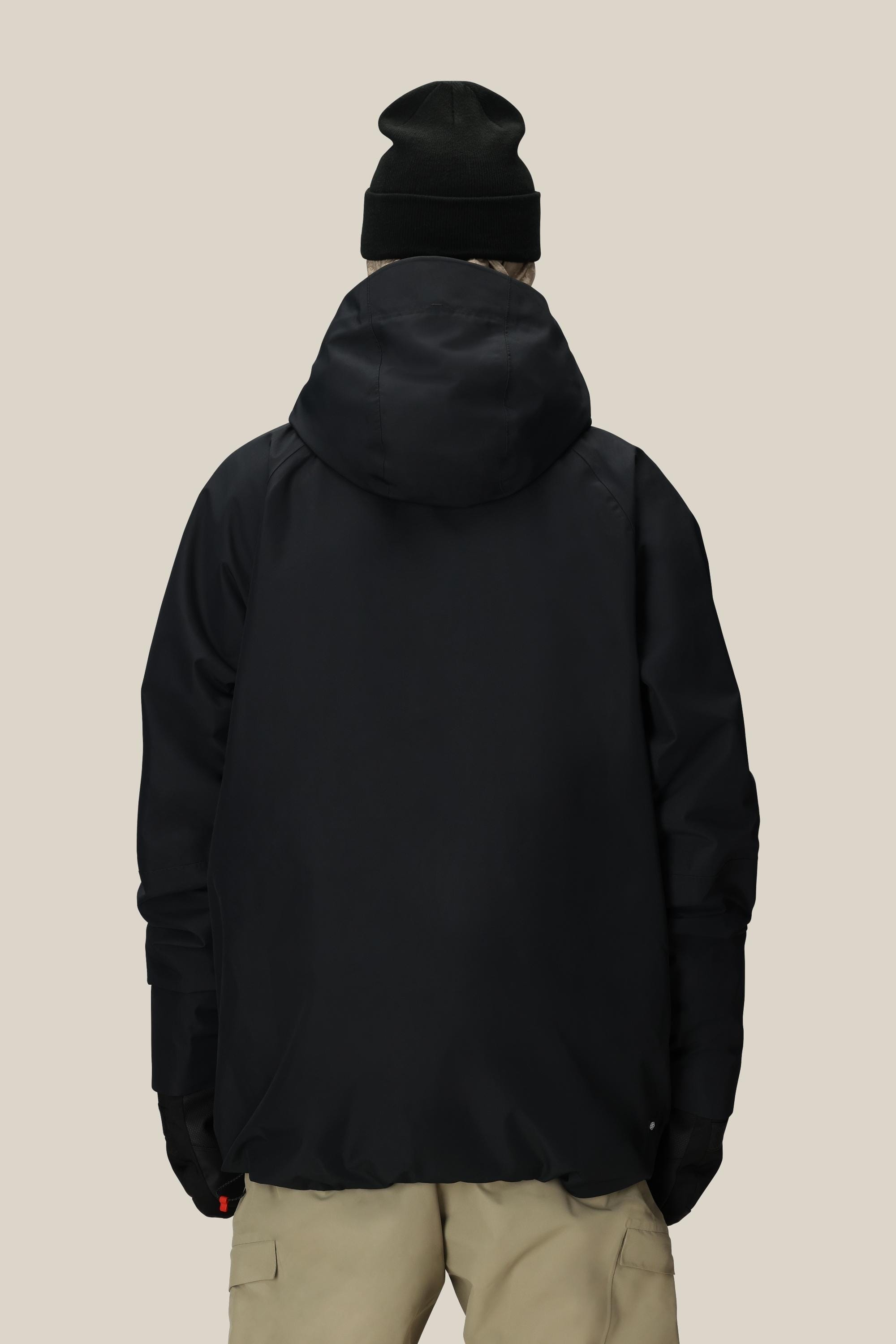 A person is shown from the back against a beige background wearing the 686 Men's Hydra™ Thermagraph® Jacket, black gloves, a black beanie, and light-colored pants.