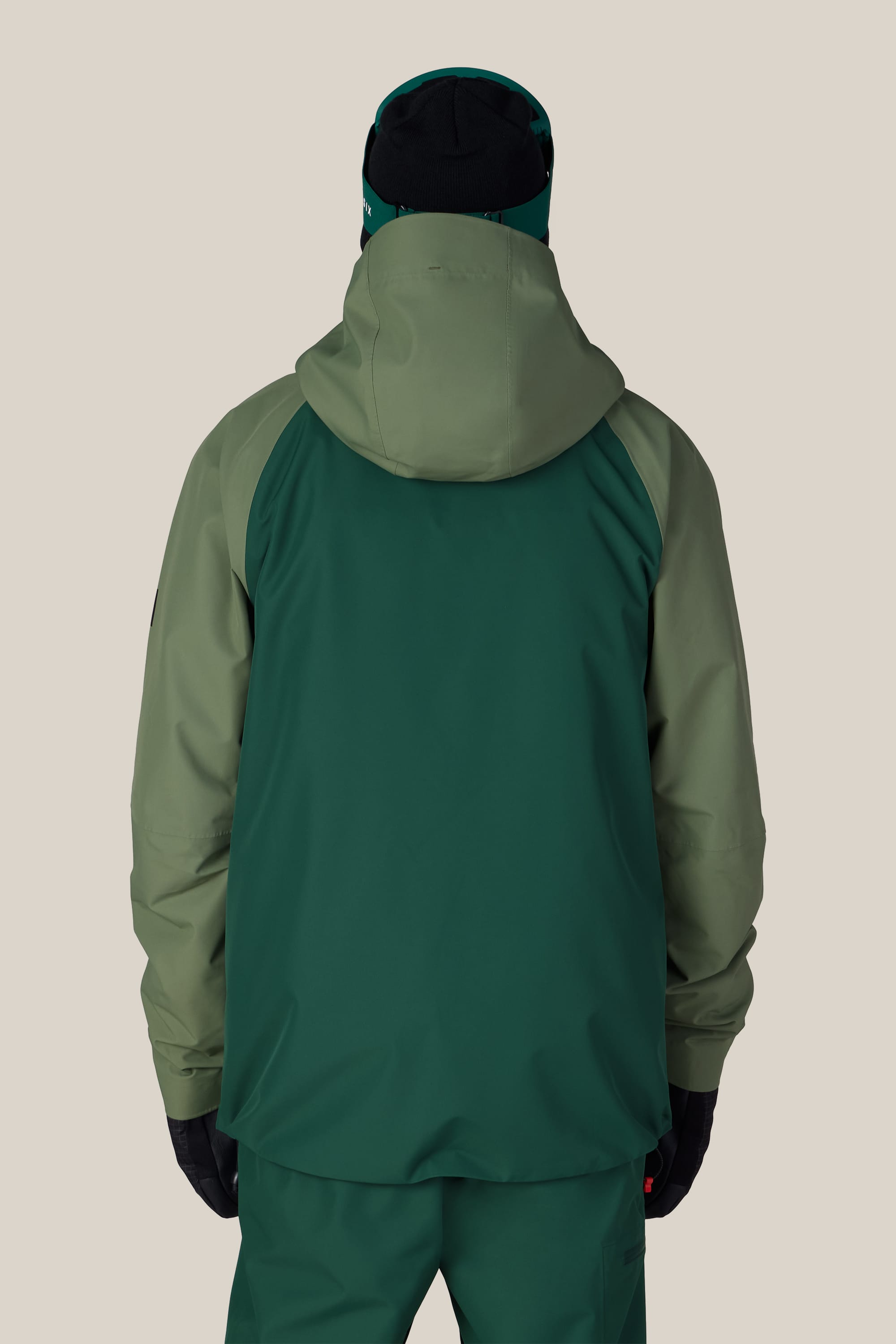 A person wearing the 686 Men’s Hydra™ Thermagraph® Jacket by 686 stands facing away against a plain beige background.