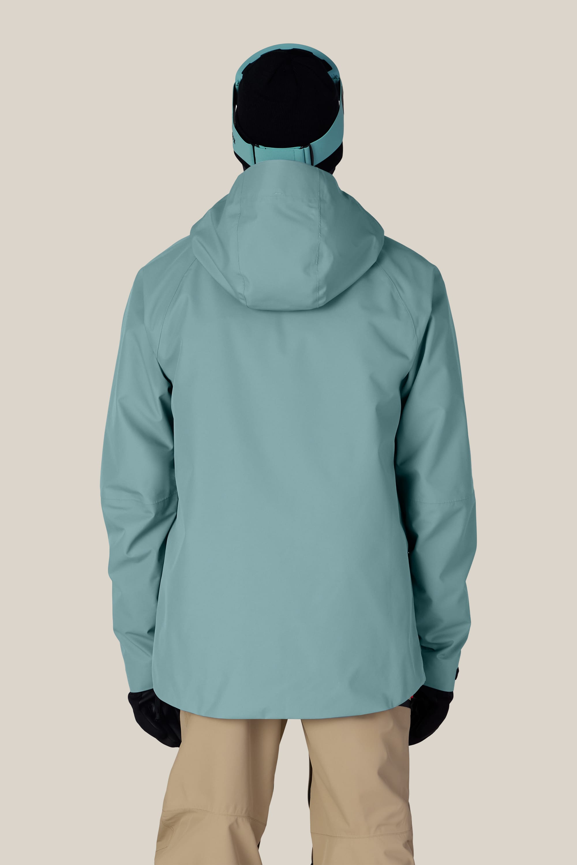 A person is shown from the back against a plain, light background, wearing the 686 Men’s Hydra™ Thermagraph® Jacket by 686 in light blue, paired with beige pants, black gloves, and a black hat.