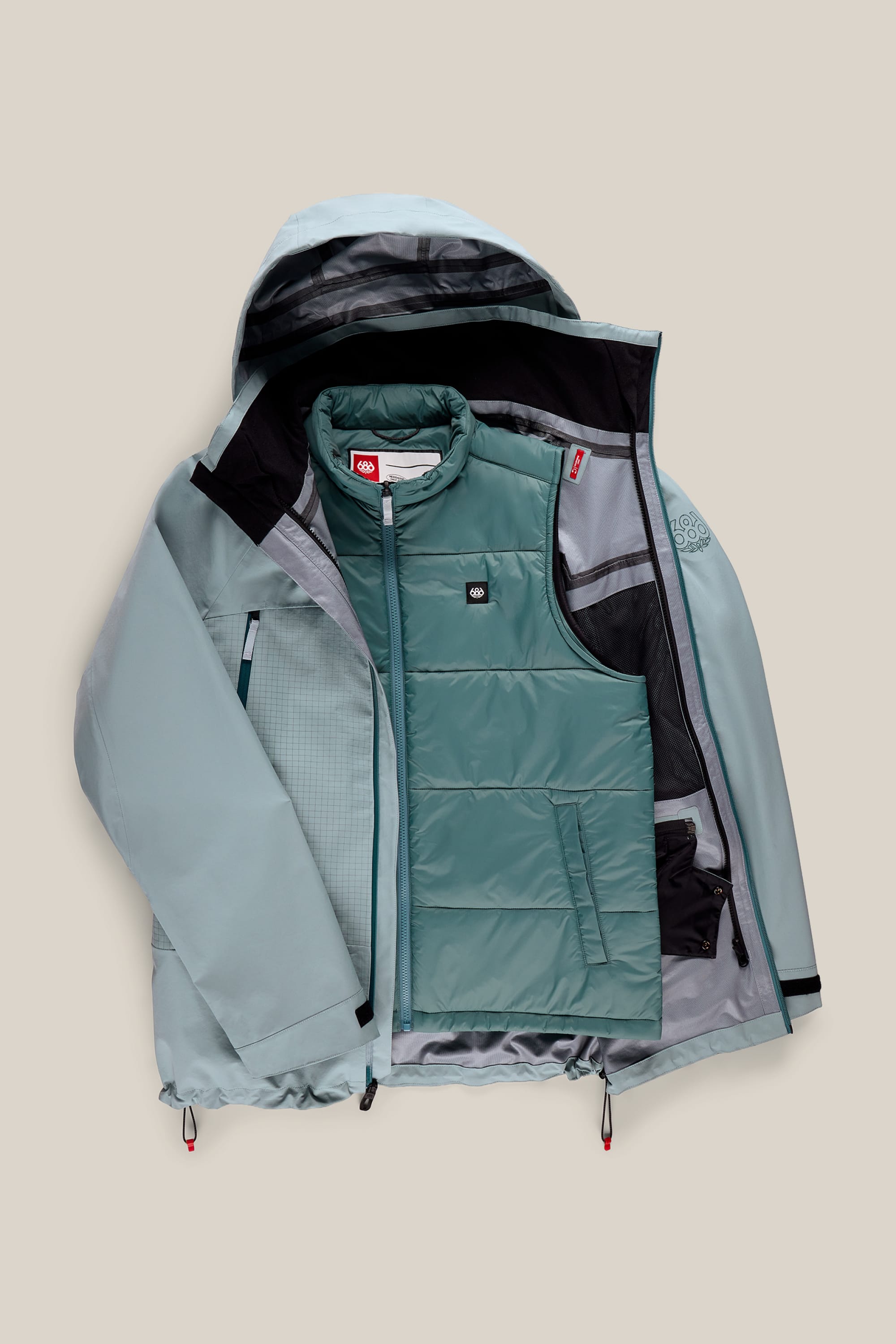 The 686 Men’s SMARTY® 3-In-1 Rodeo™ 3L Jacket by 686 is shown in light blue, featuring a hood and black zipper accents. The jacket is opened to display its quilted, teal-green inner vest. Adjustable cords and multiple layers provide warmth and weather protection.