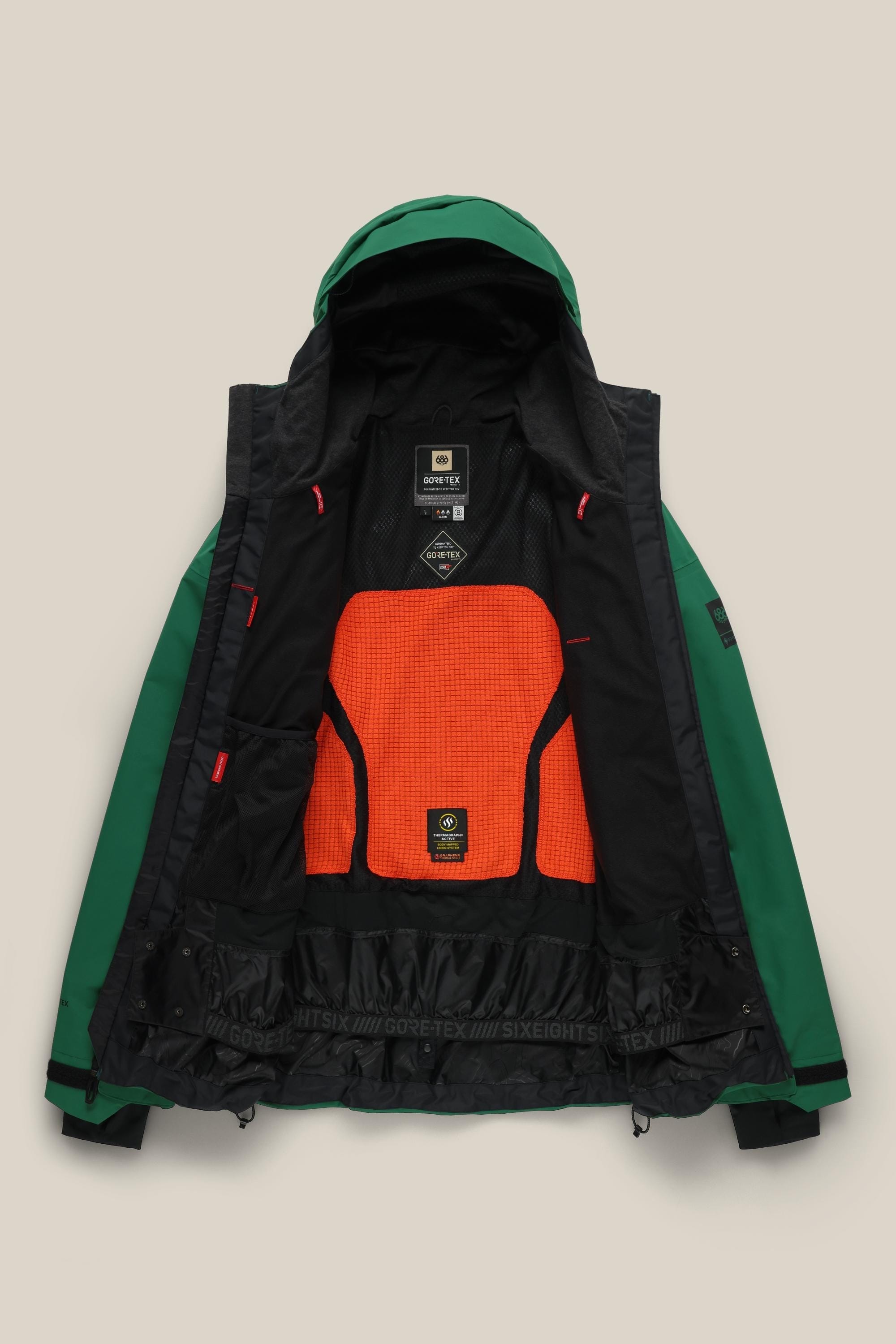 The 686 Men's GORE-TEX GT Thermagraph® Jacket is a green waterproof woven jacket with a hood, bright orange mesh back panel, black inner lining, neck and waist labels, and adjustable cuffs. Made by 686 with GORE-TEX material.