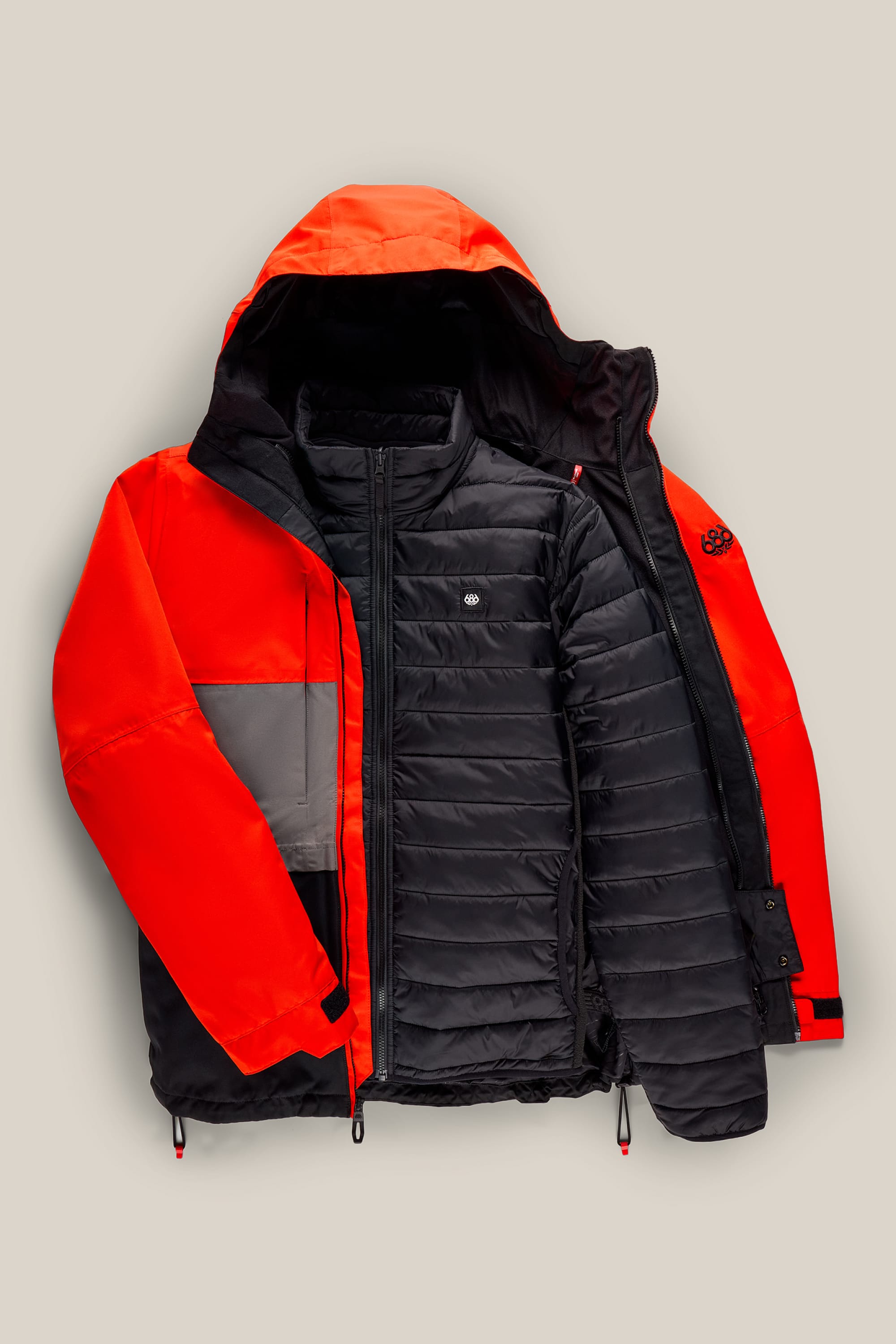 The 686 Men’s SMARTY® 3-In-1 Form Jacket by 686, featuring a red and black color scheme with a gray accent on one sleeve, is shown unzipped to display its inner black quilted layer. The jacket is laid flat against a plain beige background.