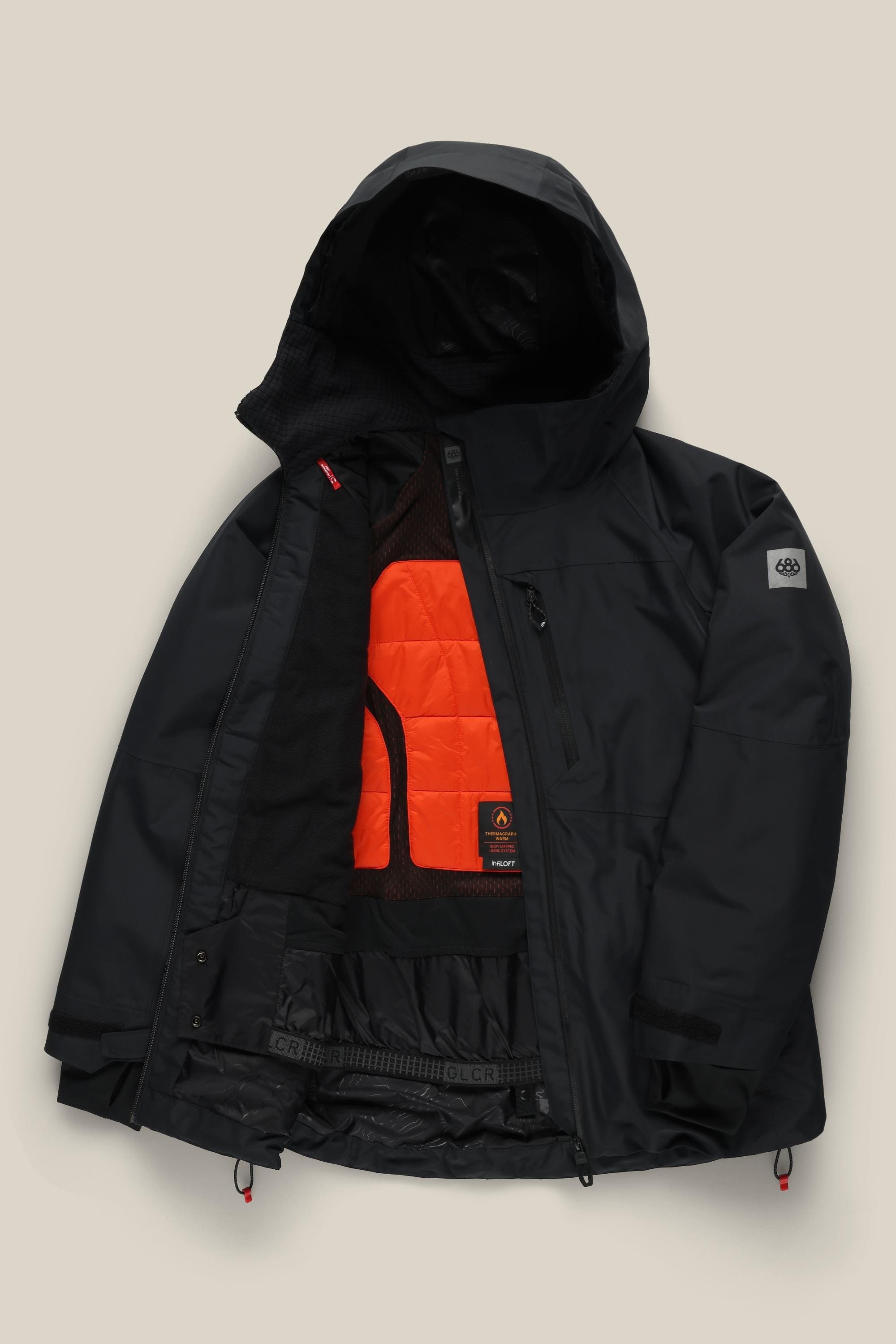 The 686 Women's Hydra™ Thermagraph® Jacket by 686 is a black polyester waterproof jacket featuring an orange insulated lining, mesh pockets, interior details, a left sleeve logo patch, and waterproof zippers.
