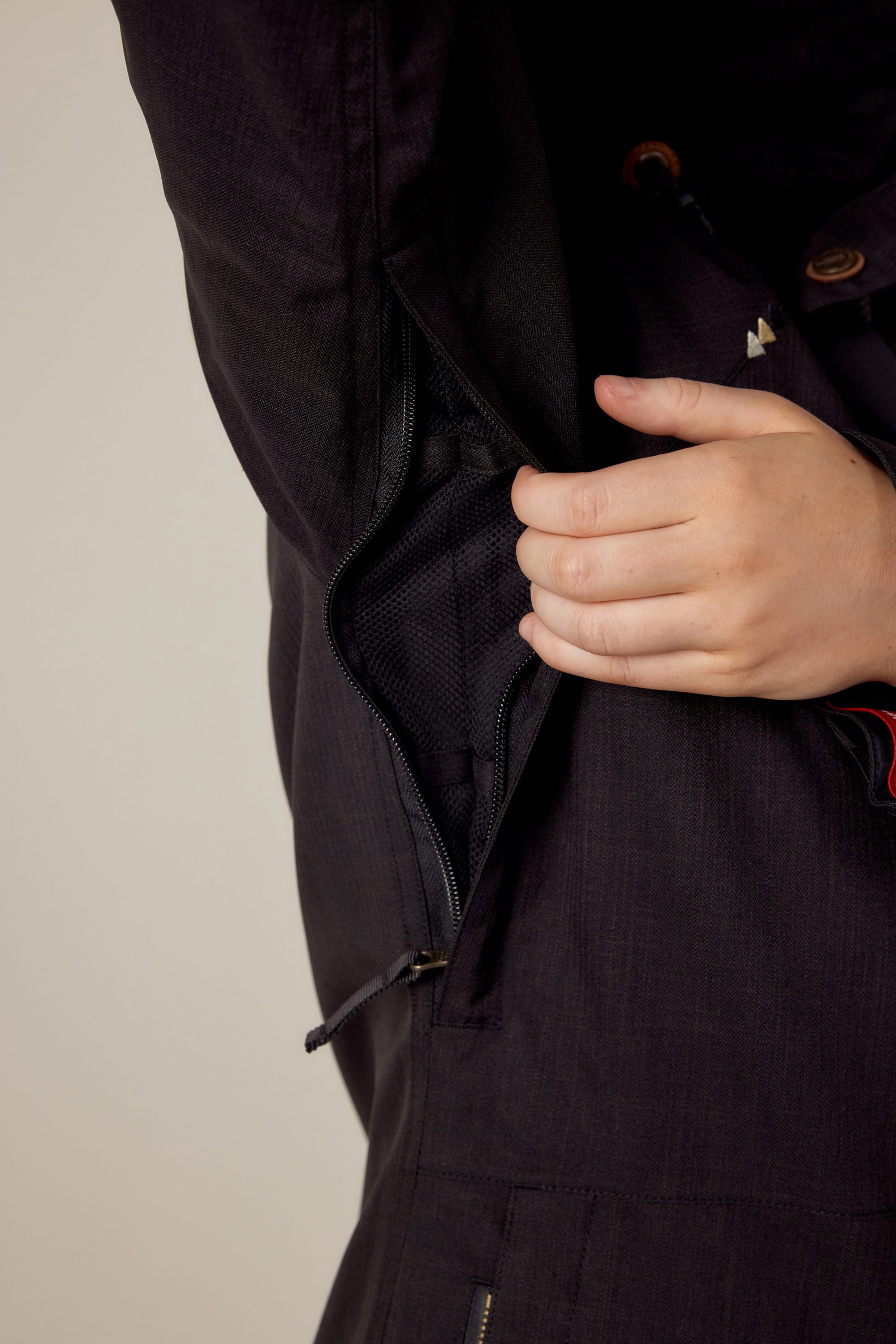 A hand unzips a hidden zipper under the arm of the 686 Women's SMARTY® 3-In-1 Spellbound Jacket, revealing its inner lining.