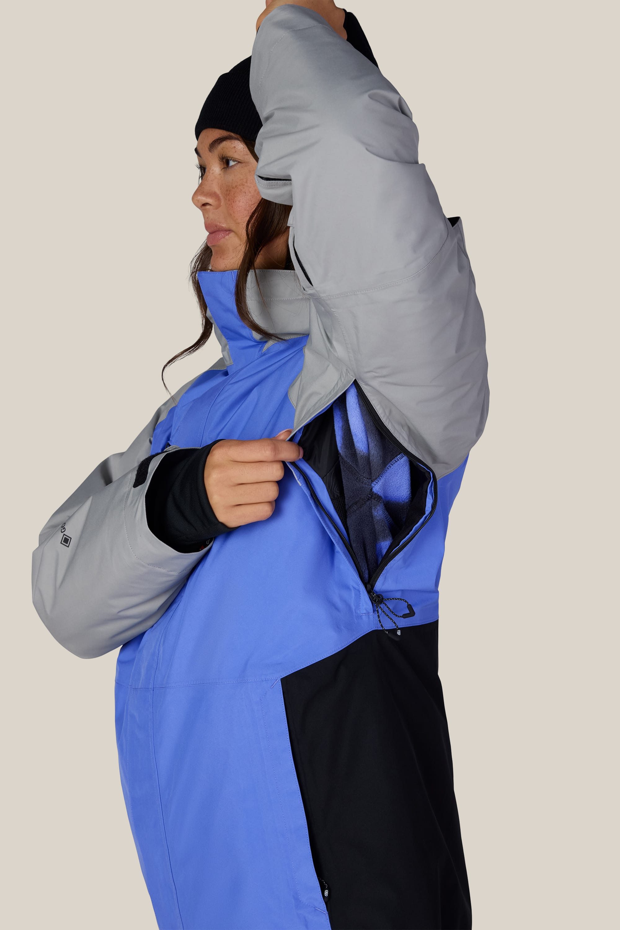 A person wearing the 686 Women’s GORE-TEX® Willow™ Insulated Jacket lifts their arm to show a zippered underarm vent, revealing a mesh lining inside.