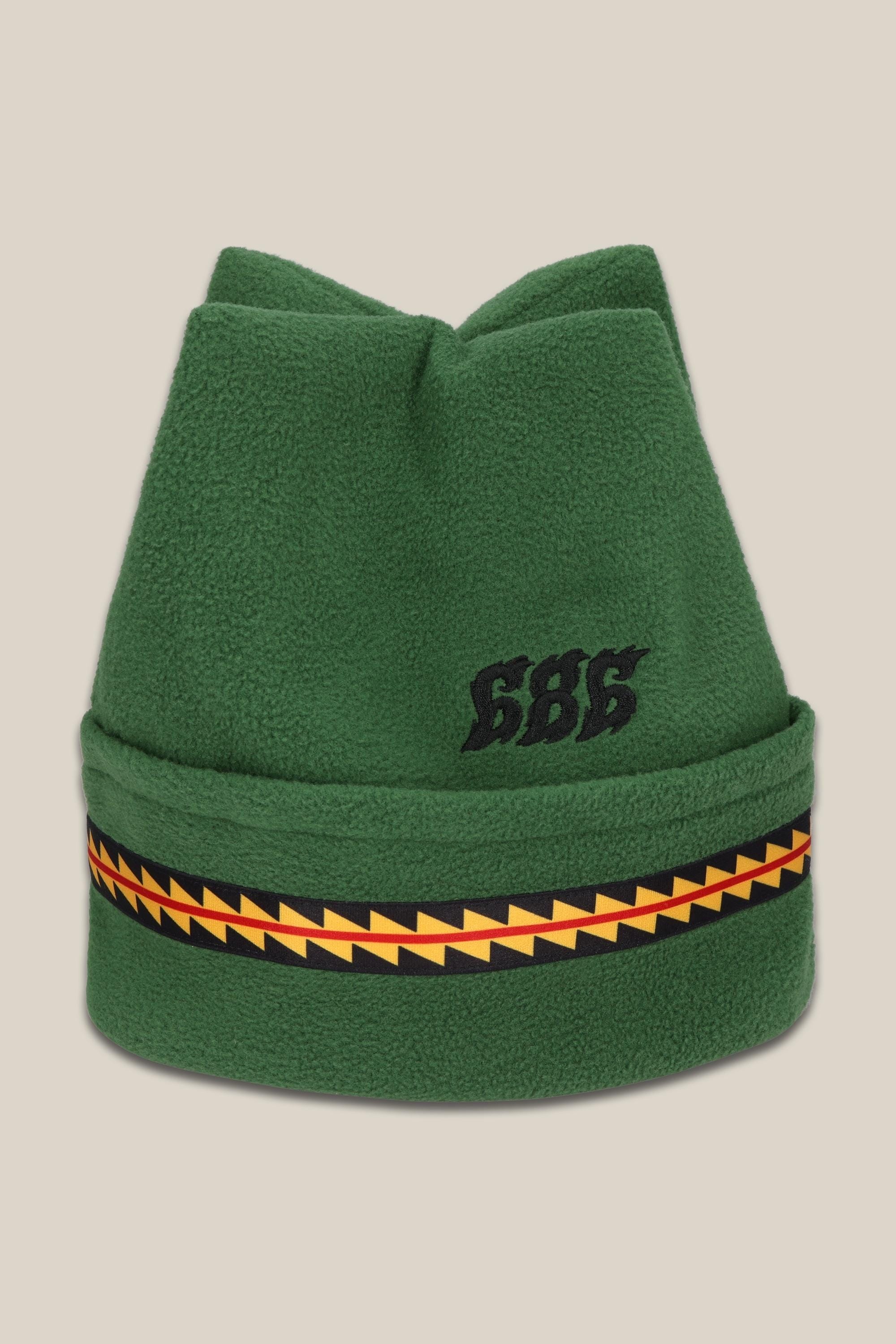 The 686 4 Points Fleece Hat by 686 features green acrylic fleece, a folded brim, a yellow and red zigzag band, and black 686 embroidery on the front. Displayed on a beige background.