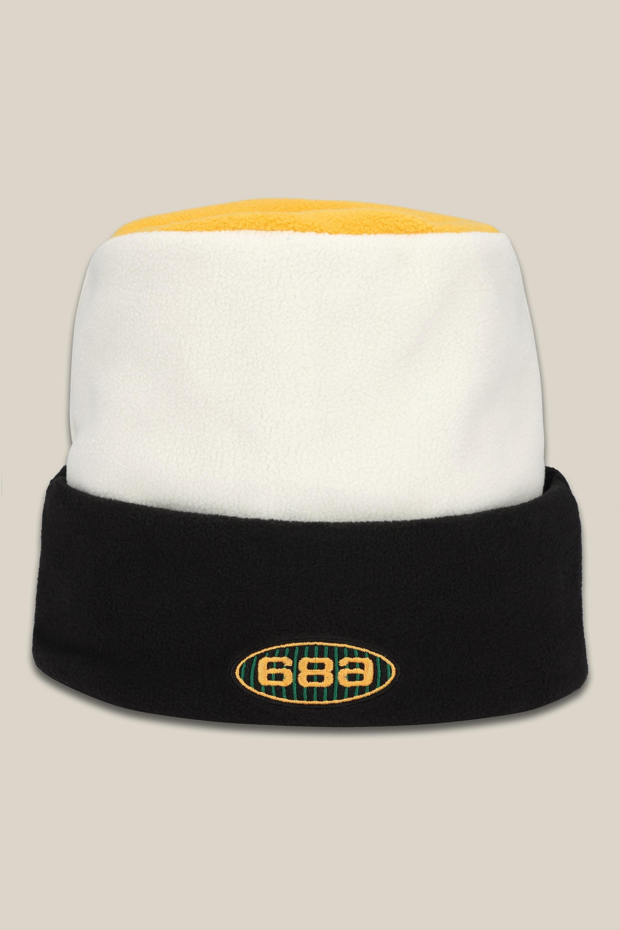 The 686 Flatop Fleece Hat is a men’s knit beanie by 686 featuring a yellow top, white middle, black fold-over brim, and an oval front logo displaying the numbers 686.