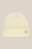 The 686 Womens Fuzzy Beanie by 686 is a soft, off-white beanie for women featuring a folded brim and a small gold circular emblem on the front, shown against a beige background.