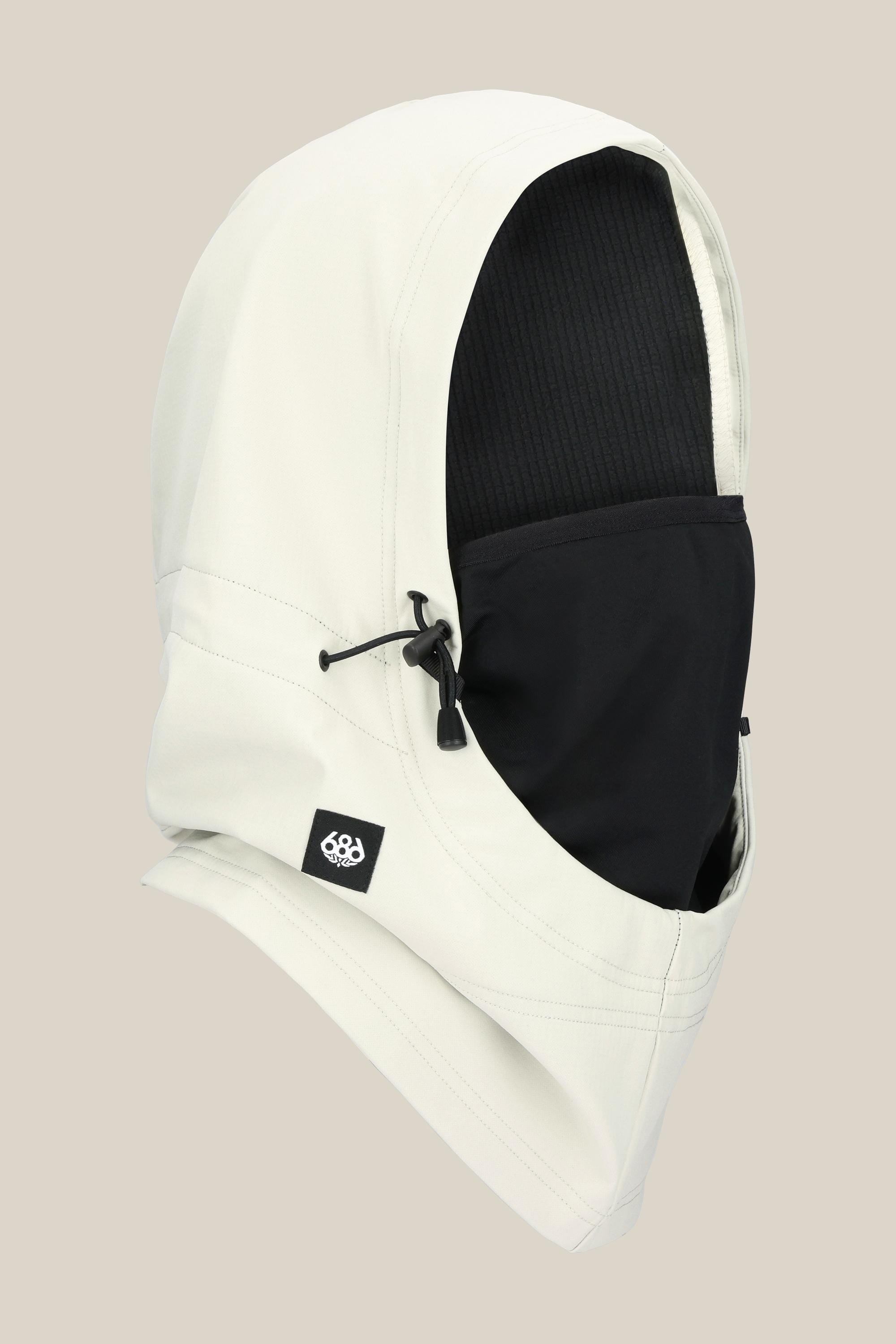 The 686 Waterproof Team Hood by 686 is a unisex facemask in white with a black face covering, crafted from soft polyester spandex. It features a drawstring adjustment and a small black logo tag, shown against a light beige background.