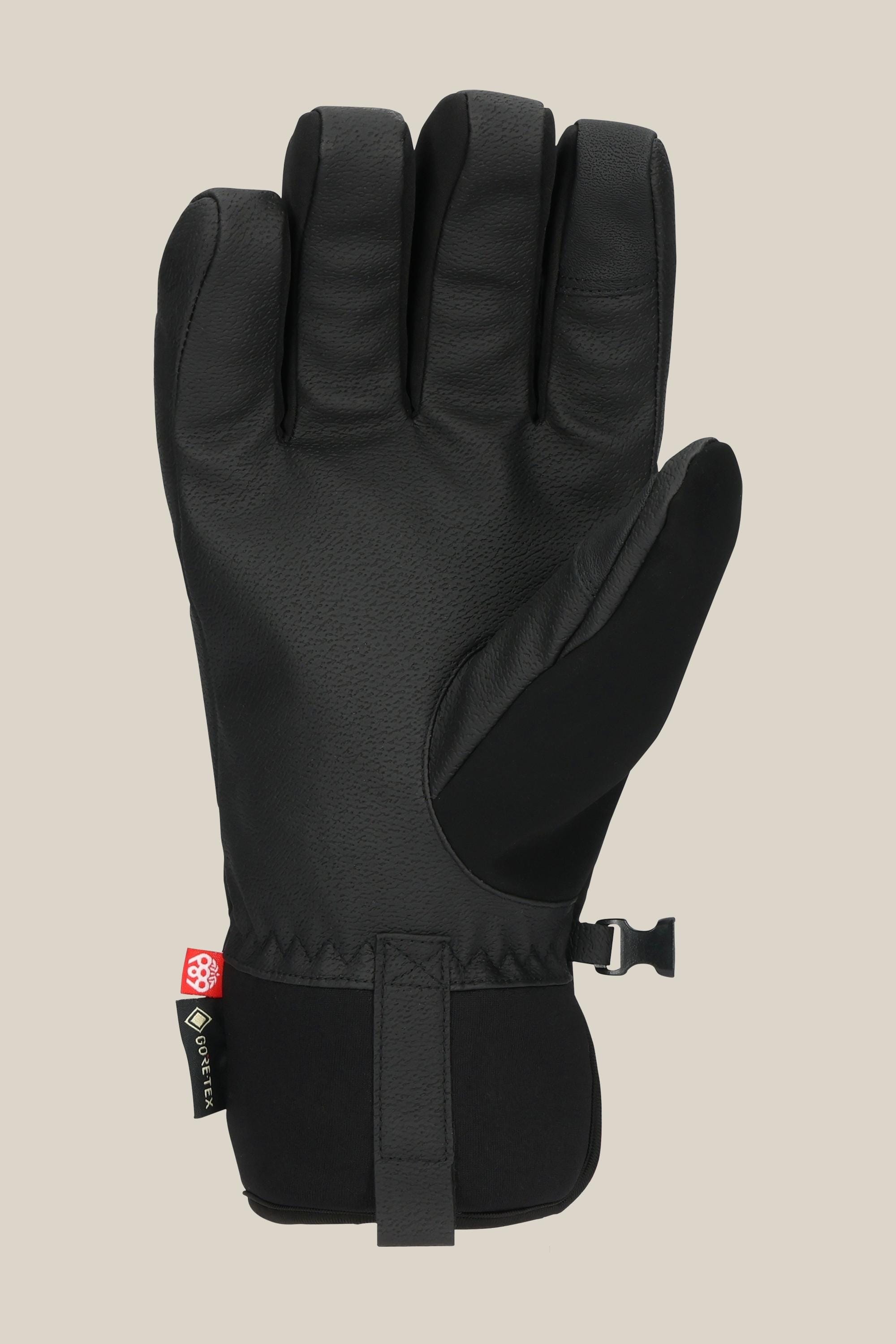 The 686 Men's GORE-TEX Linear™ Under Cuff Glove by 686 is a black insulated men’s glove with a textured palm, adjustable wrist strap, and a small fabric tag near the cuff, shown on a plain beige background.