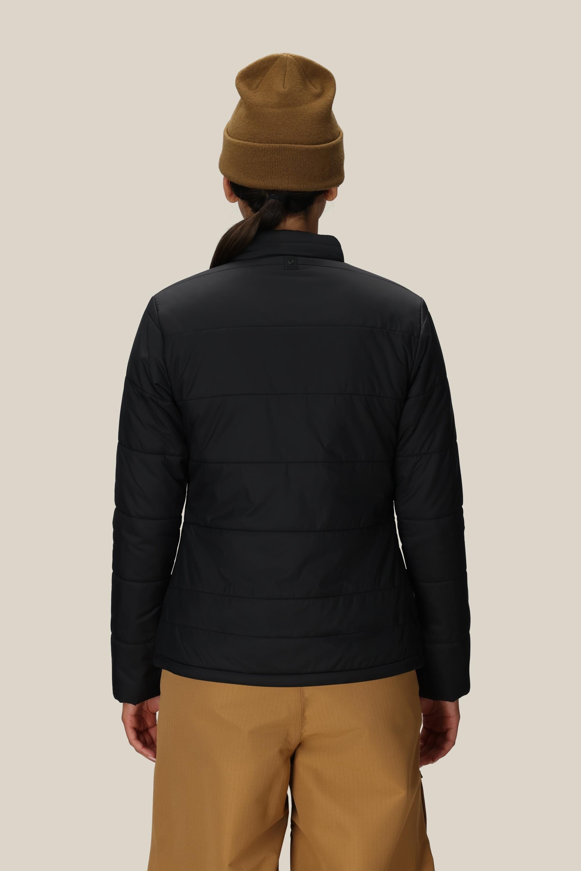 A person is shown from the back against a plain light background, wearing a brown beanie, tan pants, and the 686 Women’s Thermal Puff Insulated Jacket by 686 in black.